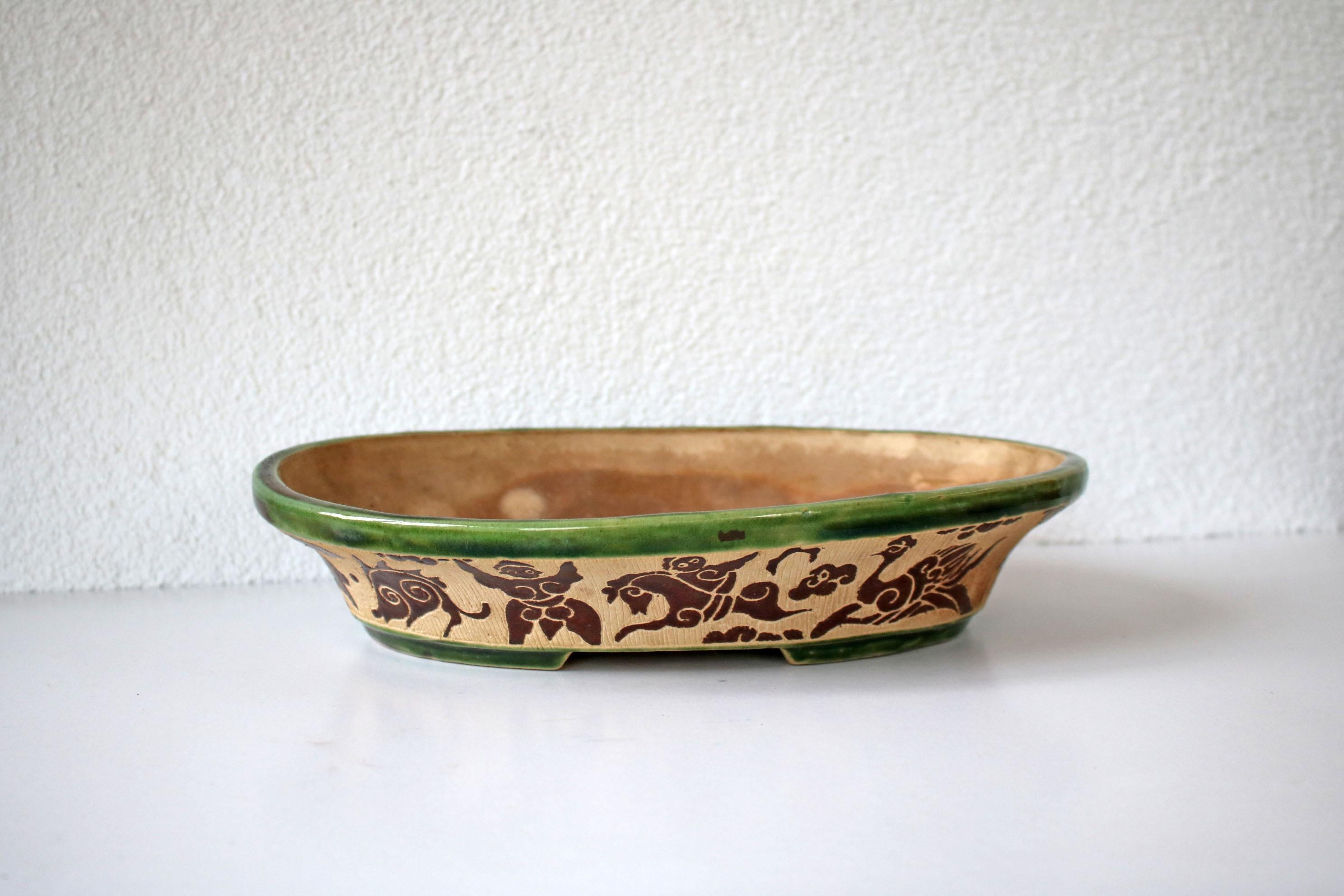 This is a beautiful ceramic glazed fruit bowl. The space around the figures was carved out by hand..