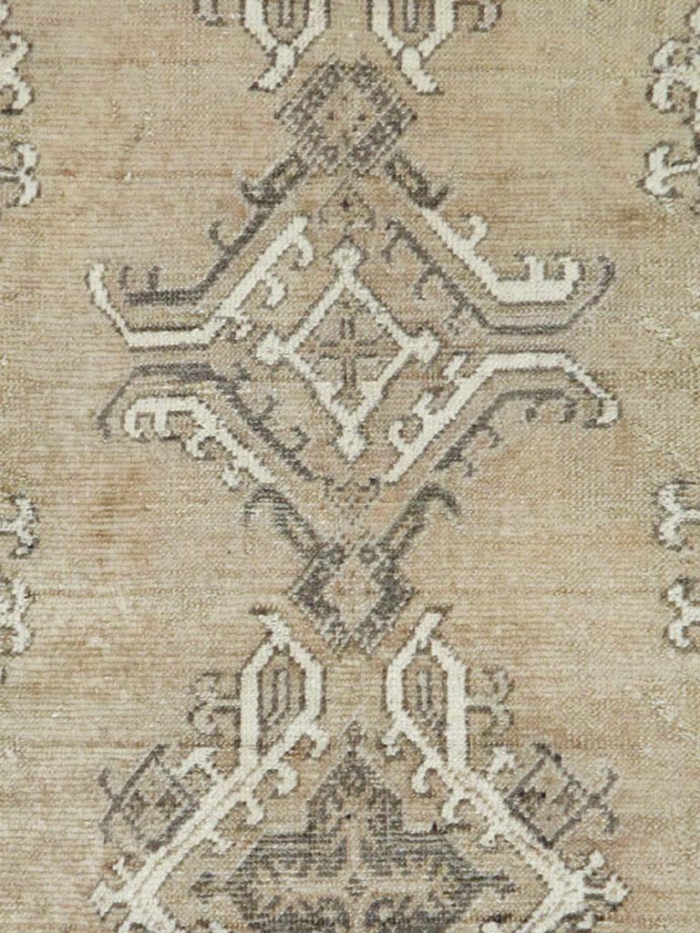 An antique Turkish Oushak carpet handmade during the early 20th century with an overall neutral and earth tone palette primarily in champagne, old ivory, and brown.