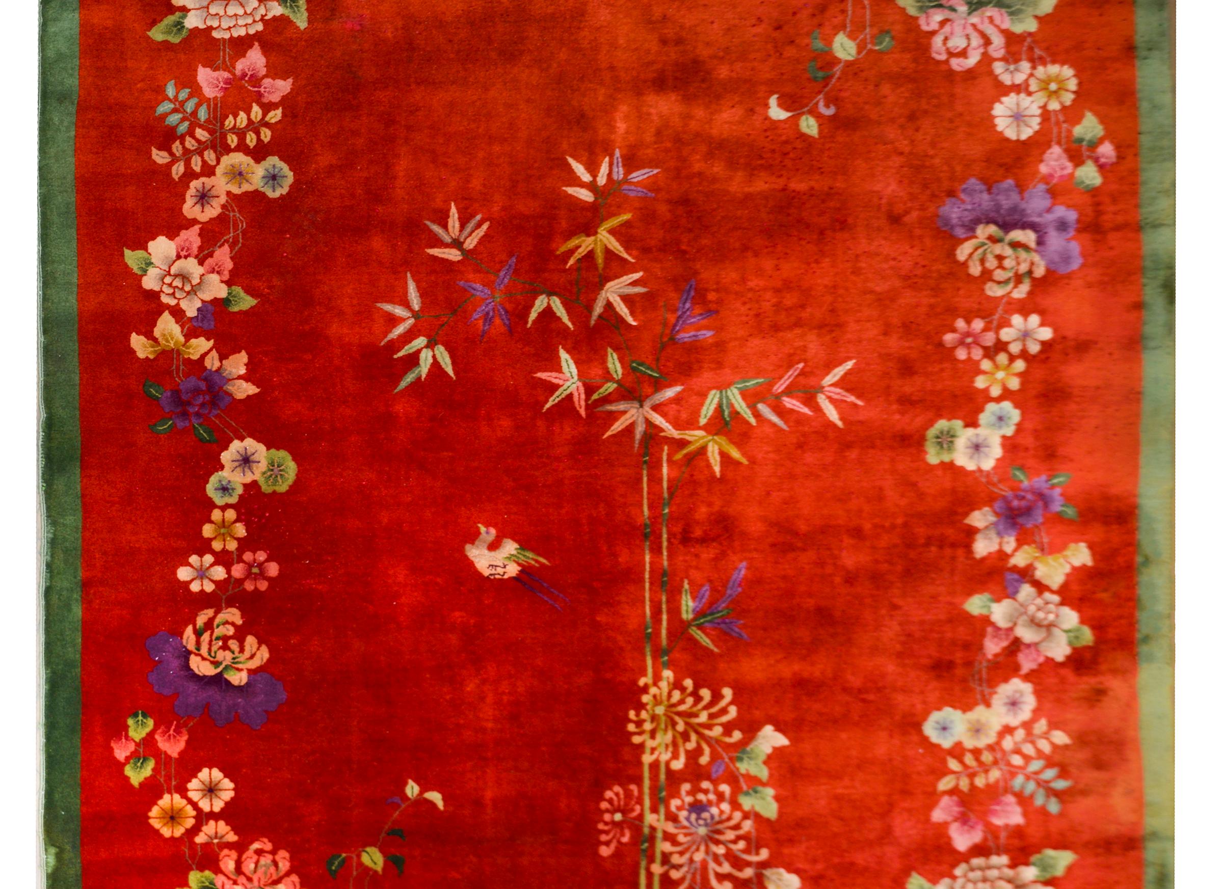 An exceptional early 20th century Chinese Art Deco rug with a bold red field surrounded by a thin green border. The field is overlaid with multicolored auspicious plants and flowers including cherry blossoms, peonies, chrysanthemum, and bamboo, each