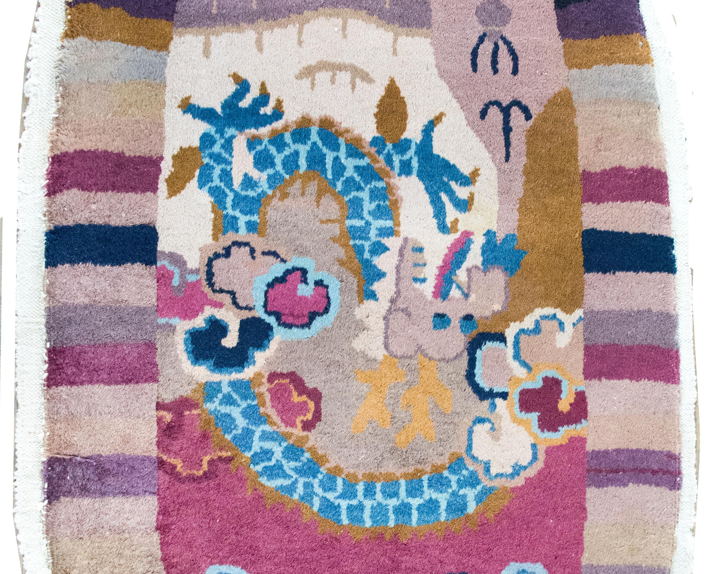 A charming early 20th century Chinese Art Deco oval rug featuring a large dragon living amidst billowing clouds in the center, with a striped border meant to mimic the suns rays, and all woven in unique vary shades of violet, pink, lavender,