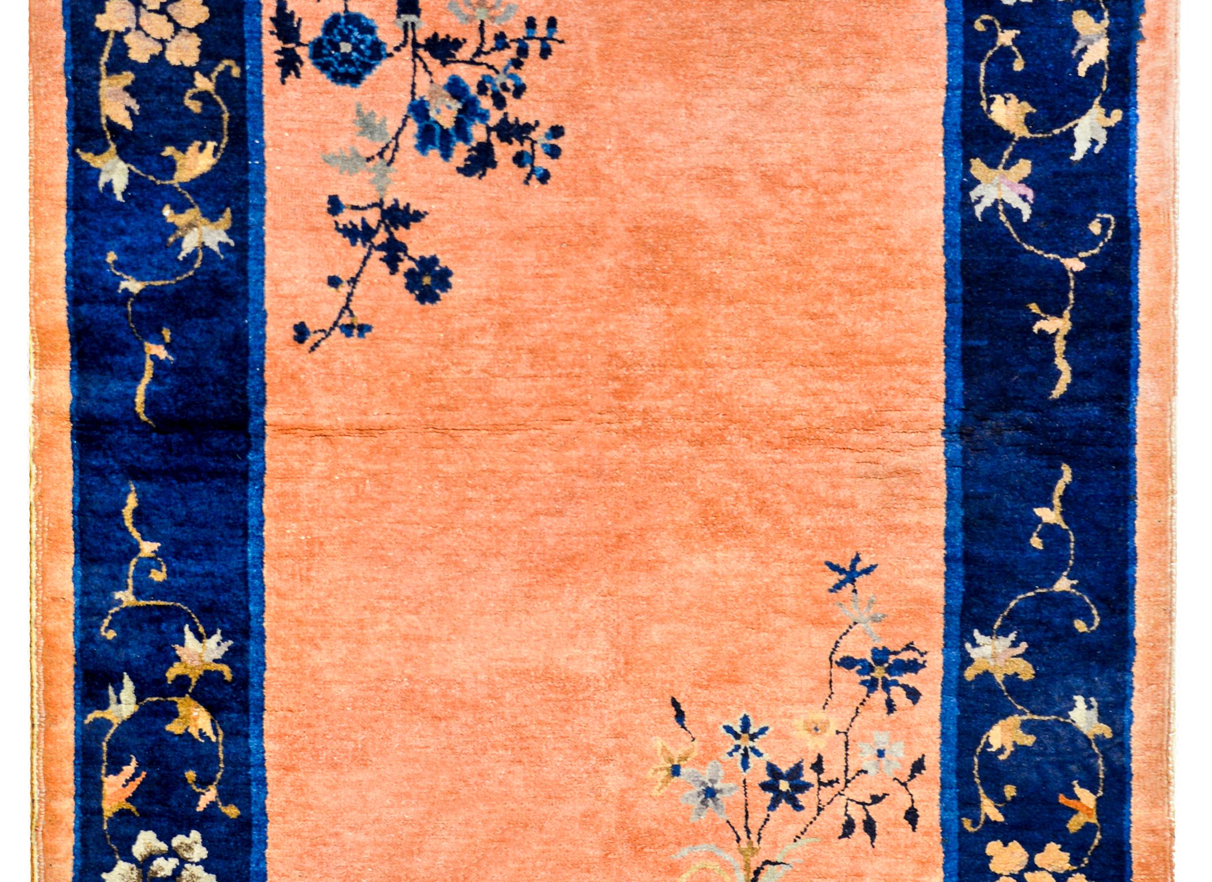 A wonderful early 20th century Chinese Art Deco rug with a salmon colored field with two vases with potted peonies and chrysanthemums in opposite corners. The border is wide with a two-tone indigo stripe covered in large peonies and scrolling leaves.