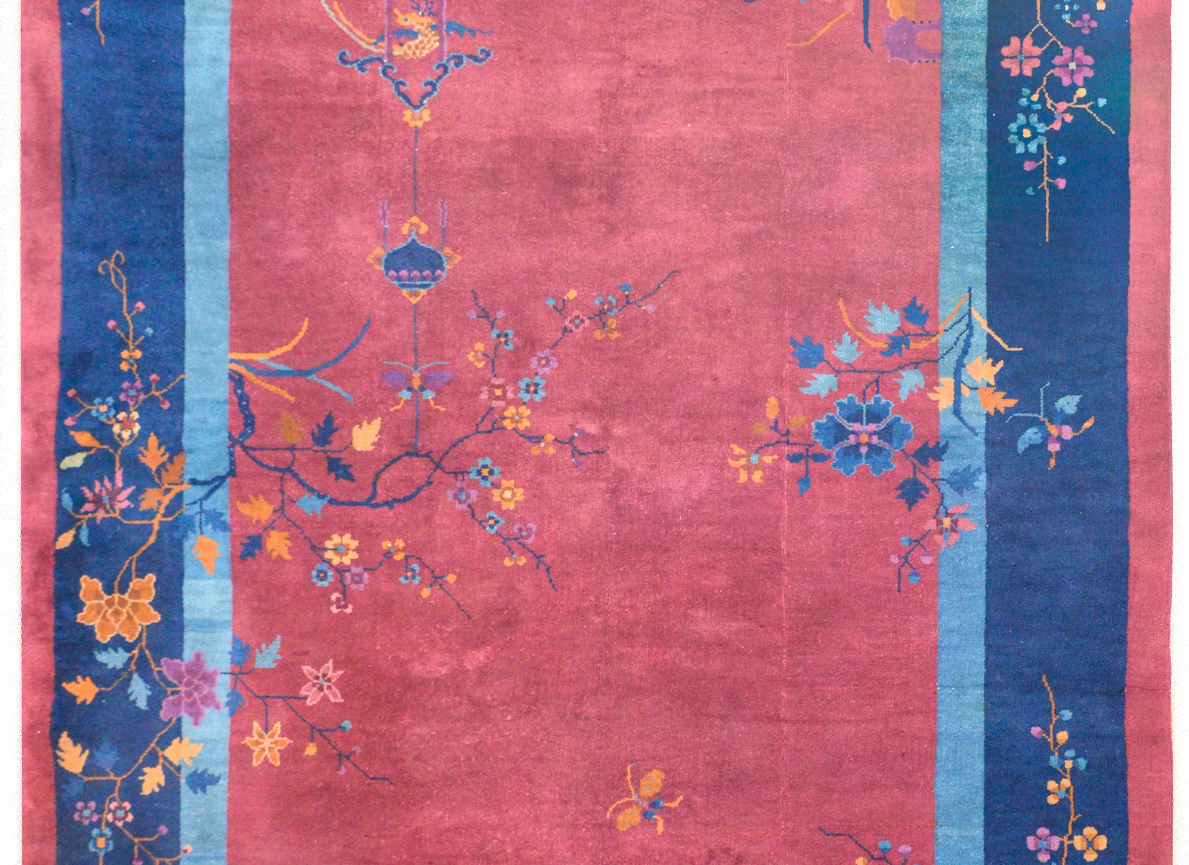 A wonderful early 20th century Chinese Art Deco rug with a cranberry field surrounded by a thin light indigo, wide dark indigo, and an outer thin cranberry stripe border. The field is overlaid with myriad multicolored flowers including