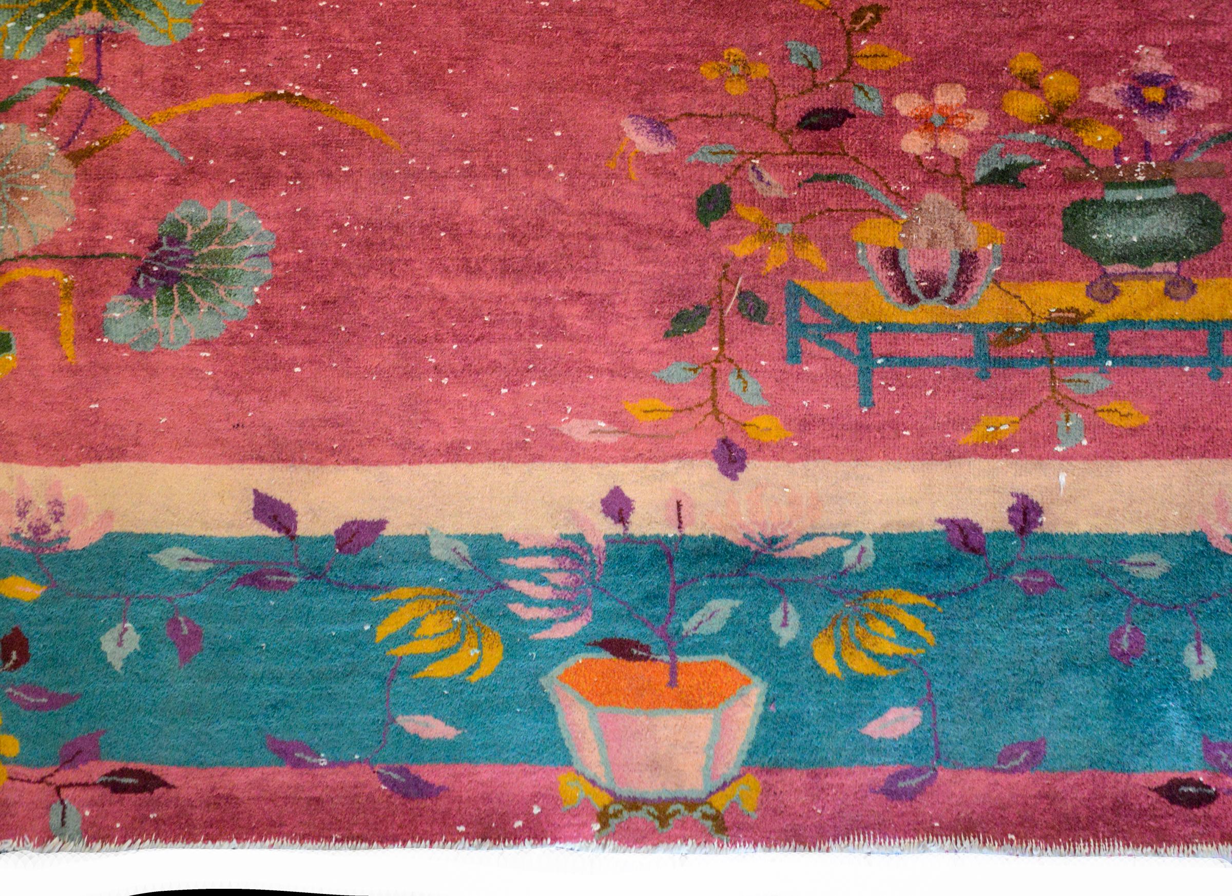 A wonderful bold early 20th century Chinese Art Deco rug with a fuchsia ground surrounded by a thin inner cream satire border, a wide turquoise border, and a thin outer fuchsia border. Each corner of the field shows various auspicious potted flowers