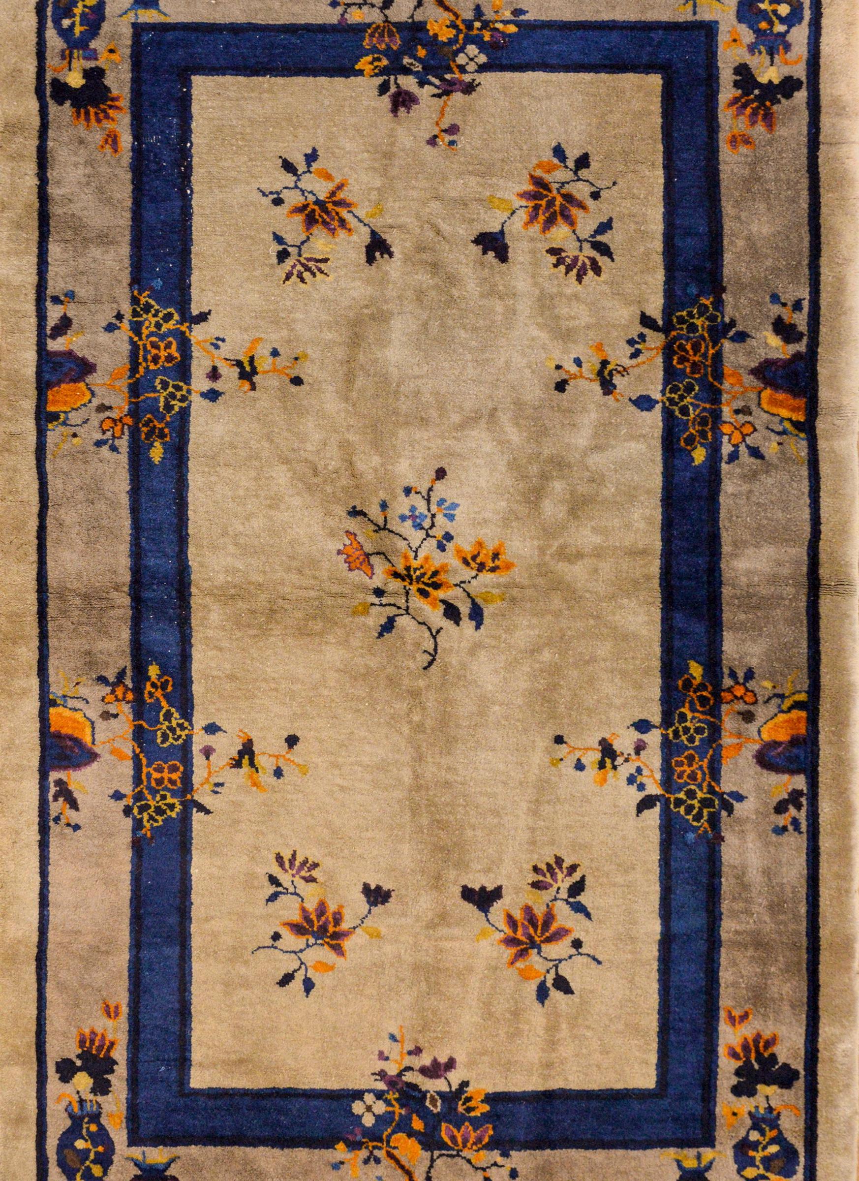 A wonderful early 20th century Chinese Art Deco rug with a gray background and thin indigo recessed border. Vases and clusters of auspicious flowers woven in orange, violet, and indigo surround the field.