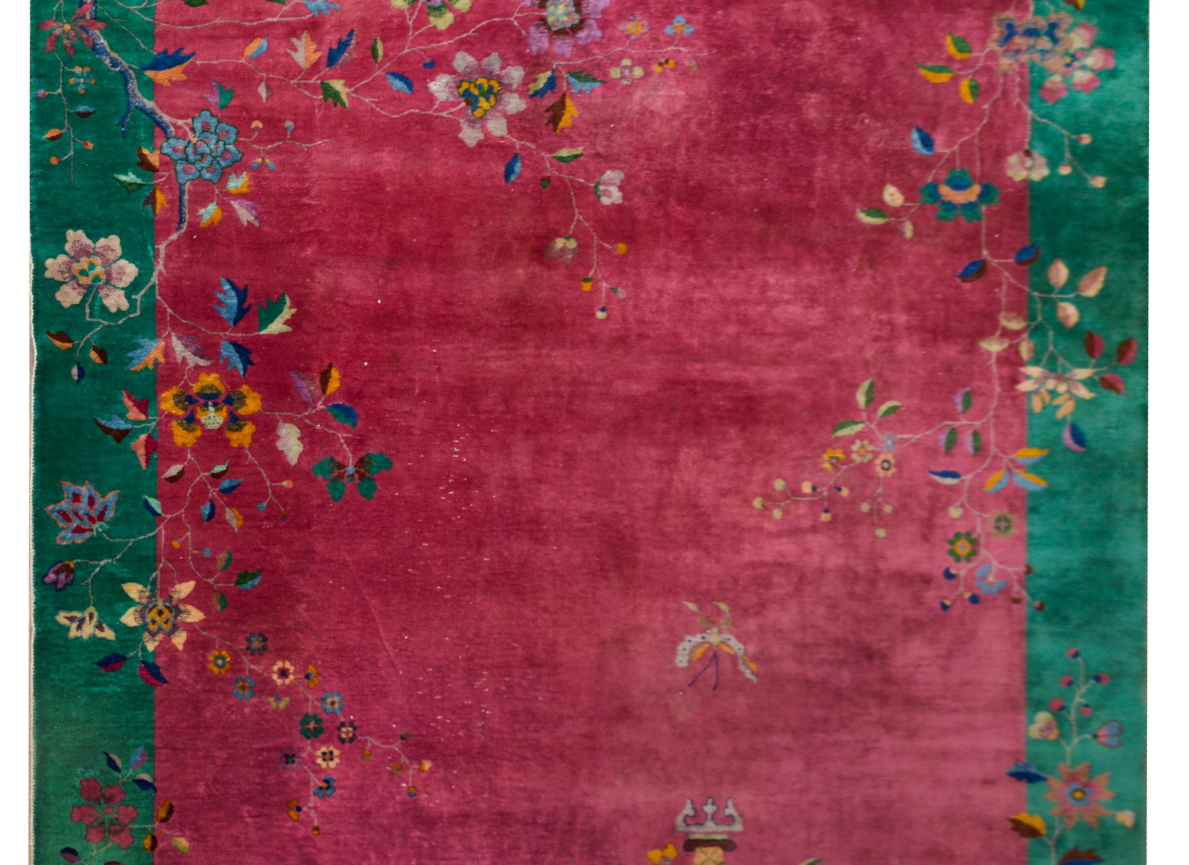 Ein chinesischer Art-Déco-Teppich aus dem frühen 20. Jahrhundert mit einem cranberryfarbenen Feld, das von einer breiten tealfarbenen Bordüre umgeben ist. Mehrfarbige Topfpfingstrosen und Kirschblüten bedecken den Rand, und ein Schmetterling