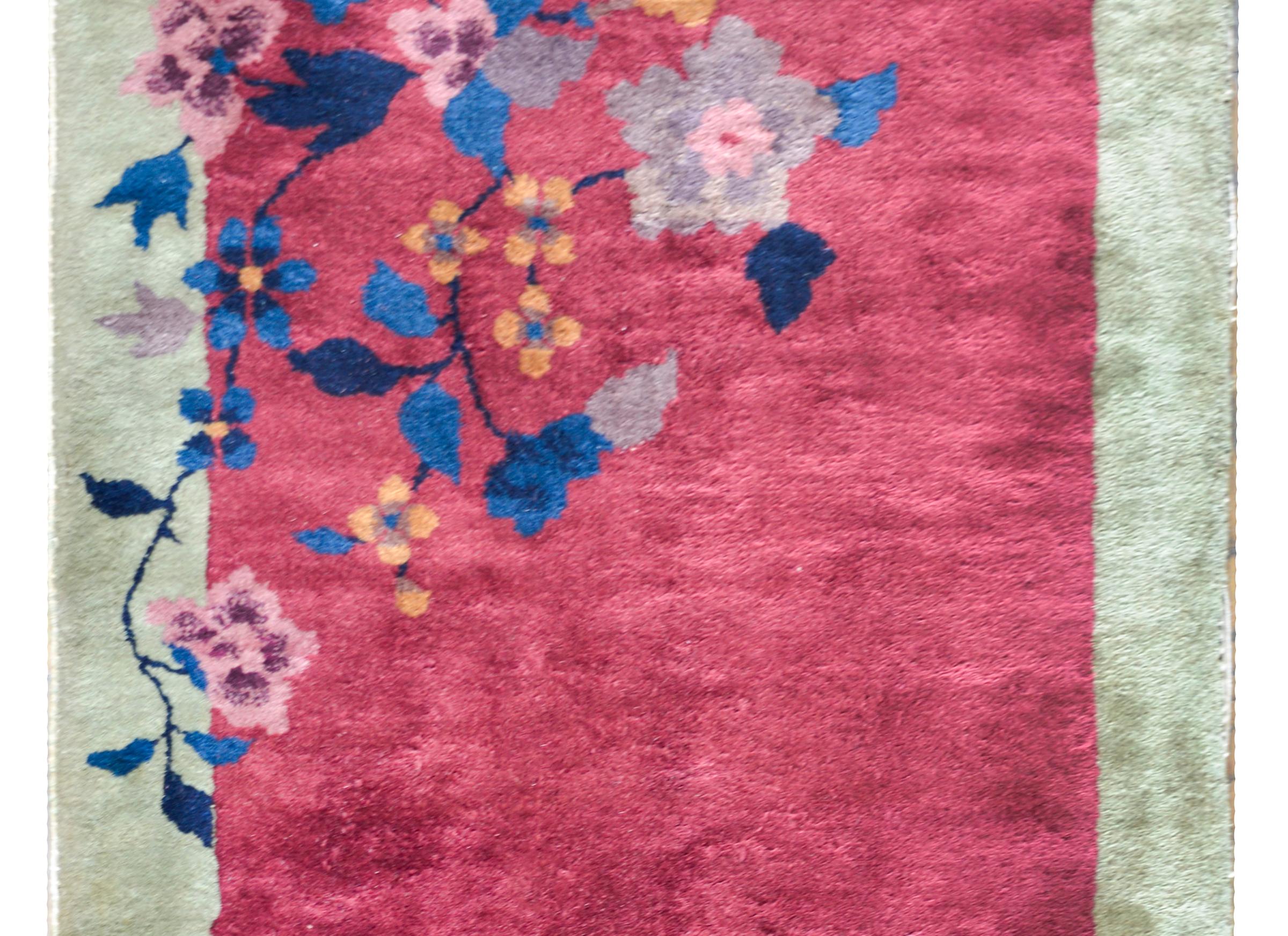 A beautiful early 20th century Chinese Art Deco rug with a cranberry field surrounded by a pale mint green border, and with each corner including indigo, gray, and pink peonies.