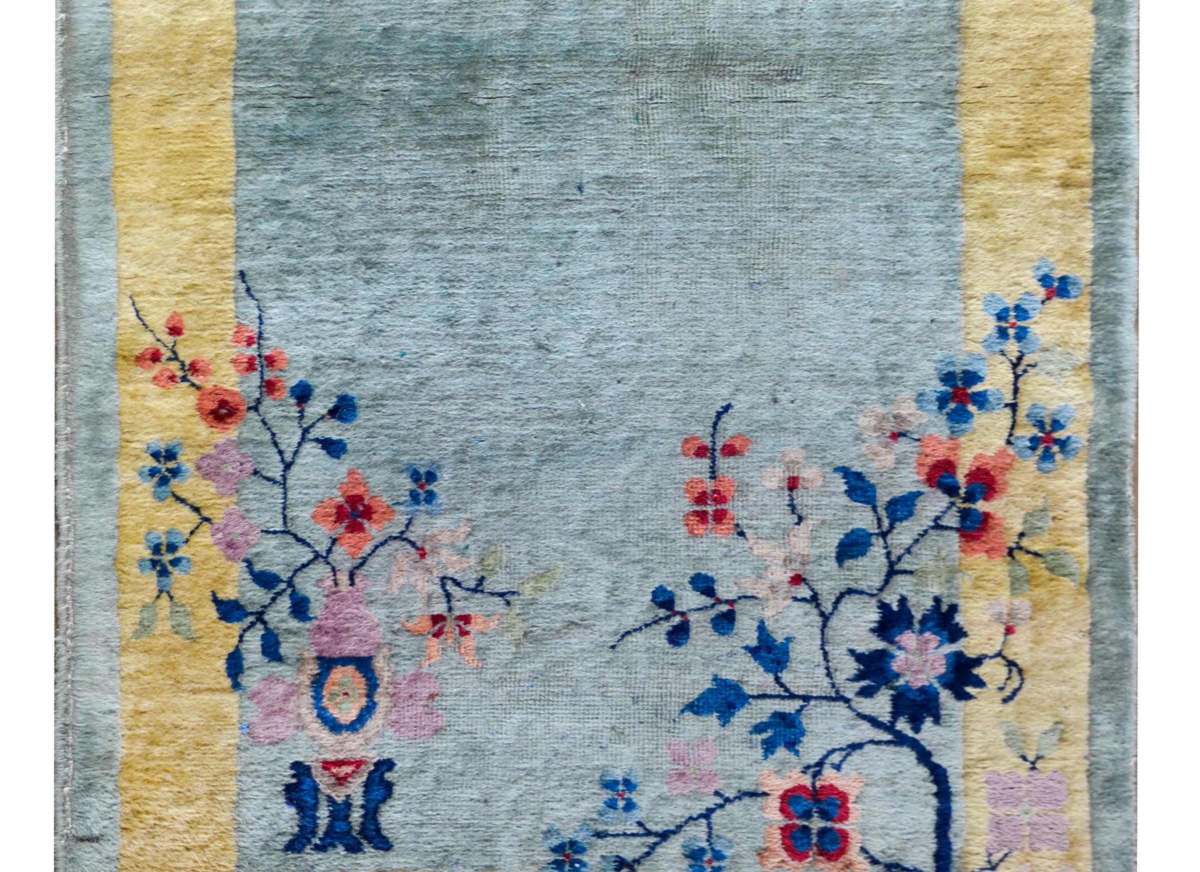 Un charmant tapis chinois Art Déco du début du 20ème siècle avec une palette de couleurs douces avec un champ vert menthe entouré d'une large bordure dorée, le tout recouvert d'une myriade de fleurs dont des pivoines, des chrysanthèmes et des fleurs