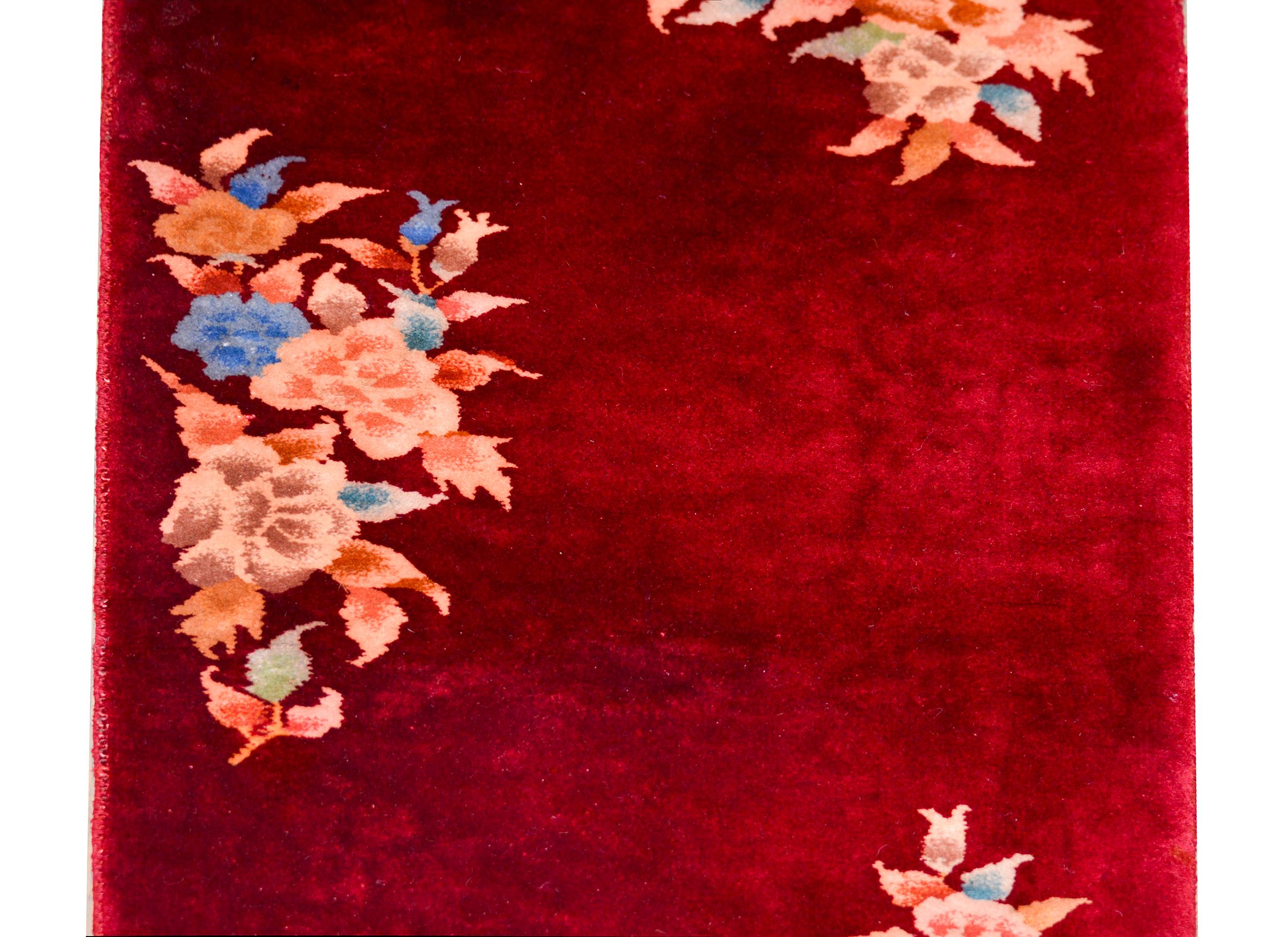 A petite Chinese Art Deco rug with a multi-colored peonies against a dark cranberry field with no border.