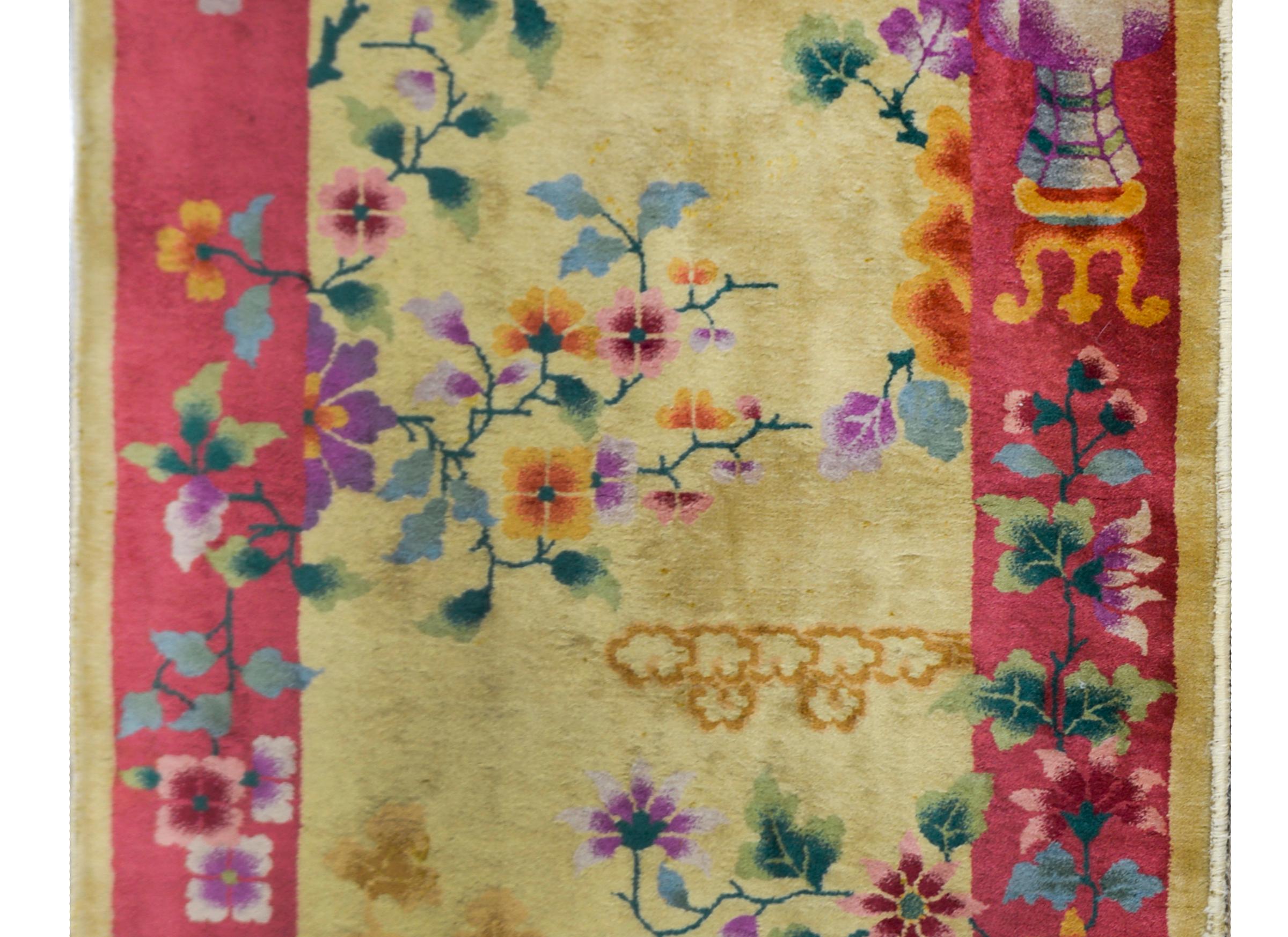 A beautiful early 20th century Chinese Art Deco rug with a champagne field surrounded by a wide mauve border, and all overlaid with multi-colored peonies, chrysanthemum, lotus, and cherry blossoms, with butterflies, and auspicious scholar's objects