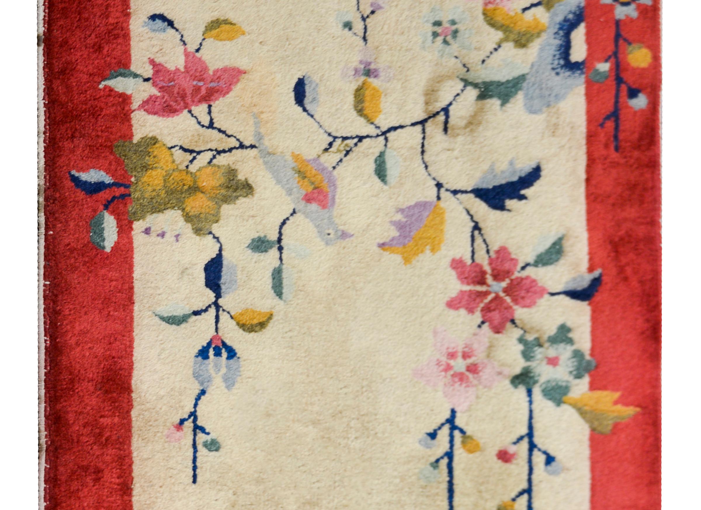 An early 20th century Chinese Art Deco rug with a champagne colored field surrounded by a white cranberry border, and overlaid with multi-colored peonies and prunus blossoms.