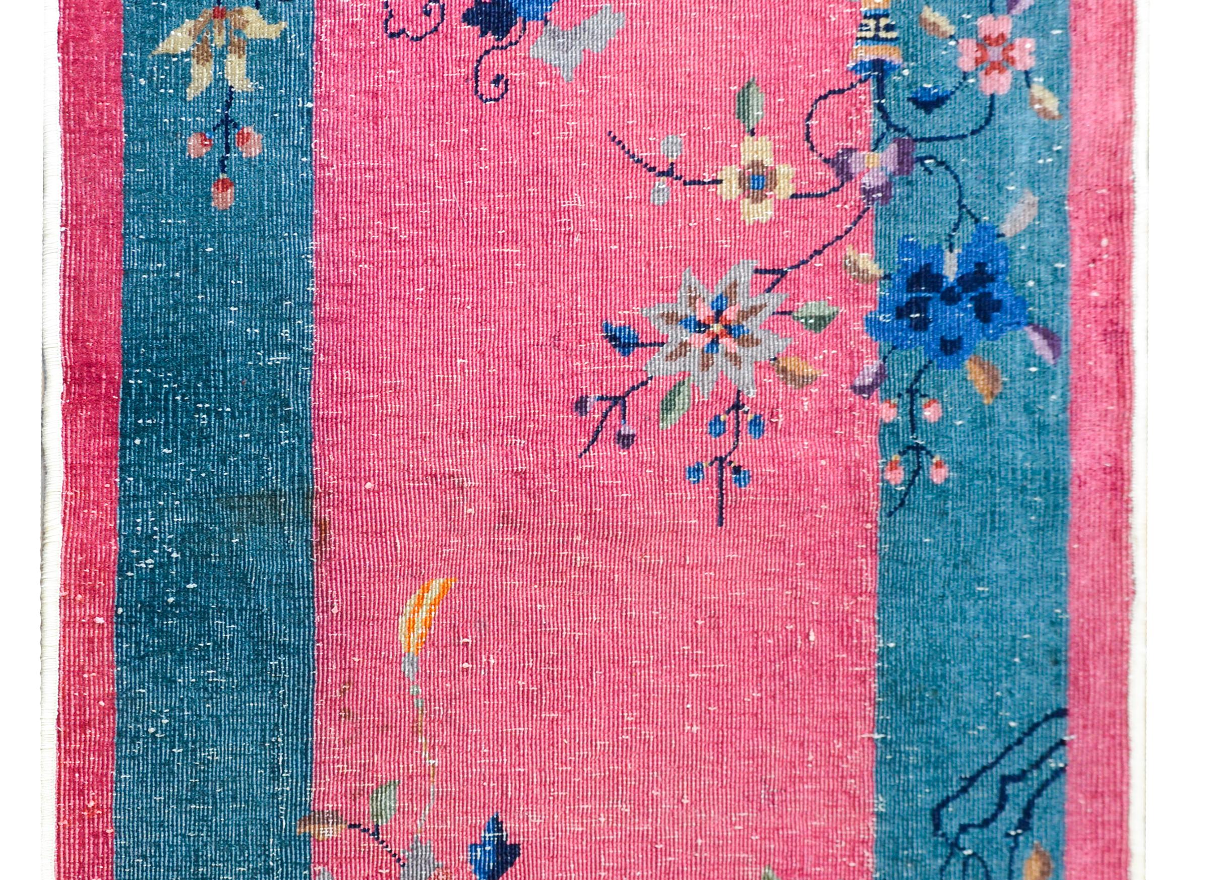 A sweet early 20th century Chinese Art Deco rug with rich pink field surrounded by a wide turquoise border, and all overlaid with auspicious flowers including peonies, chrysanthemum, and prunus.