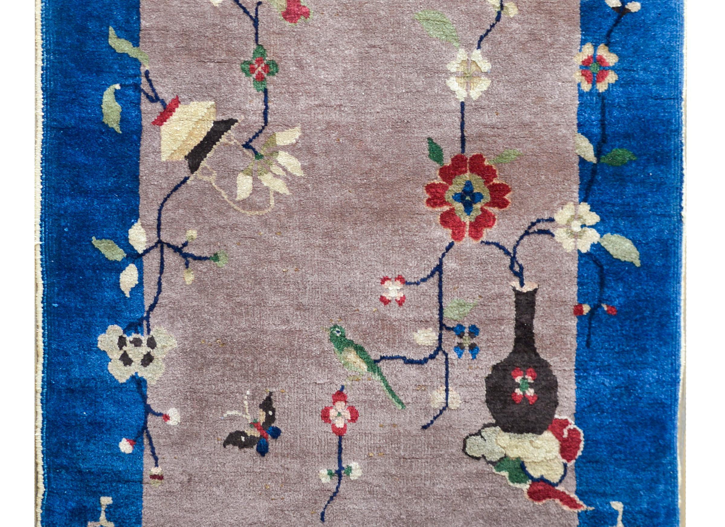 A beautiful early 20th century Chinese Art Deco rug with a gray field surrounded by a wide royal blue border. Overlaid across the entire rug are two vases potted with auspicious flowers including peonies, chrysanthemum, and prunus blossoms.