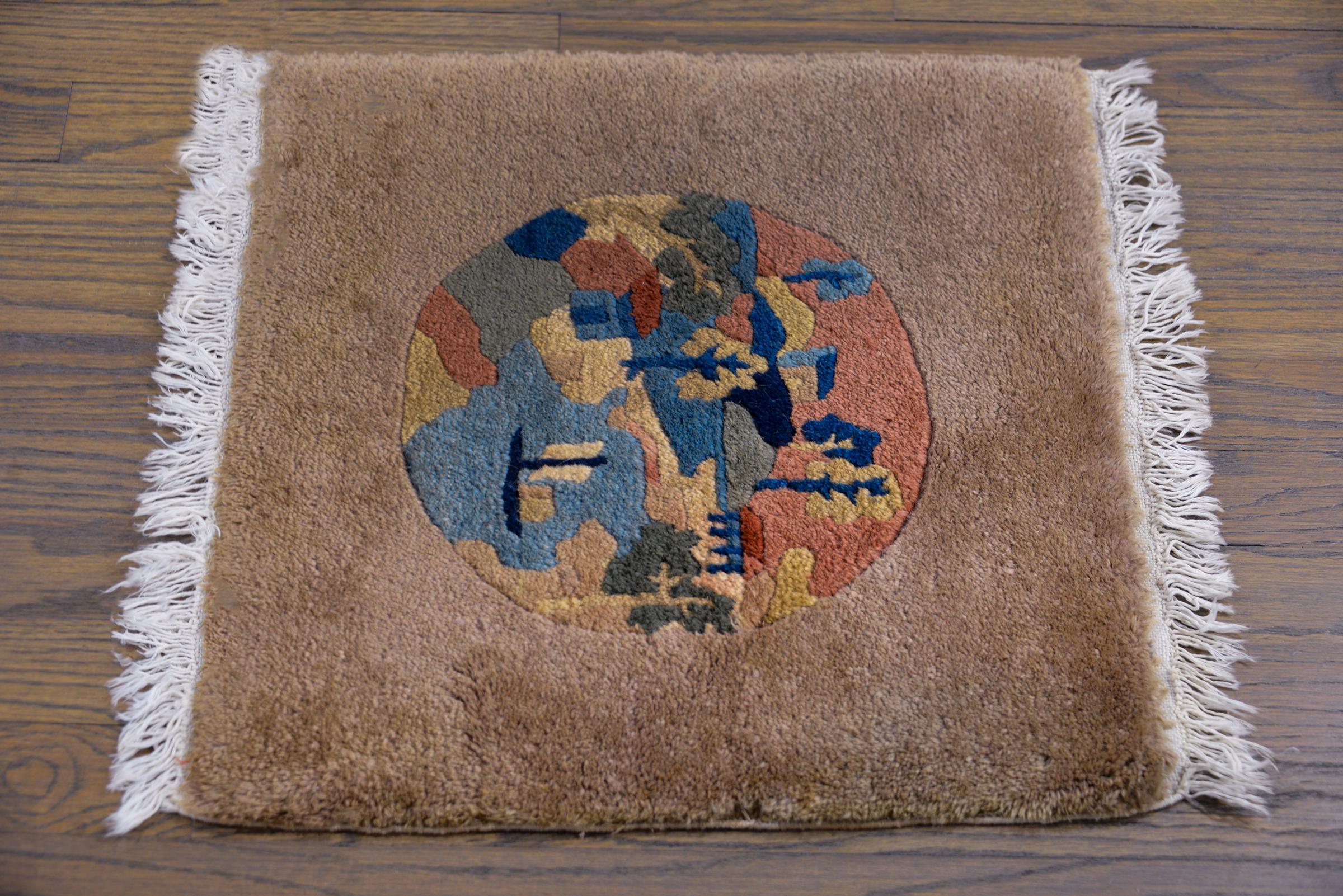 A charming early 20th century Chinese Art Deco rug with a central round medallion with a landscape containing houses surrounding a lake with a boat, and all surrounded by a wide camel colored border.