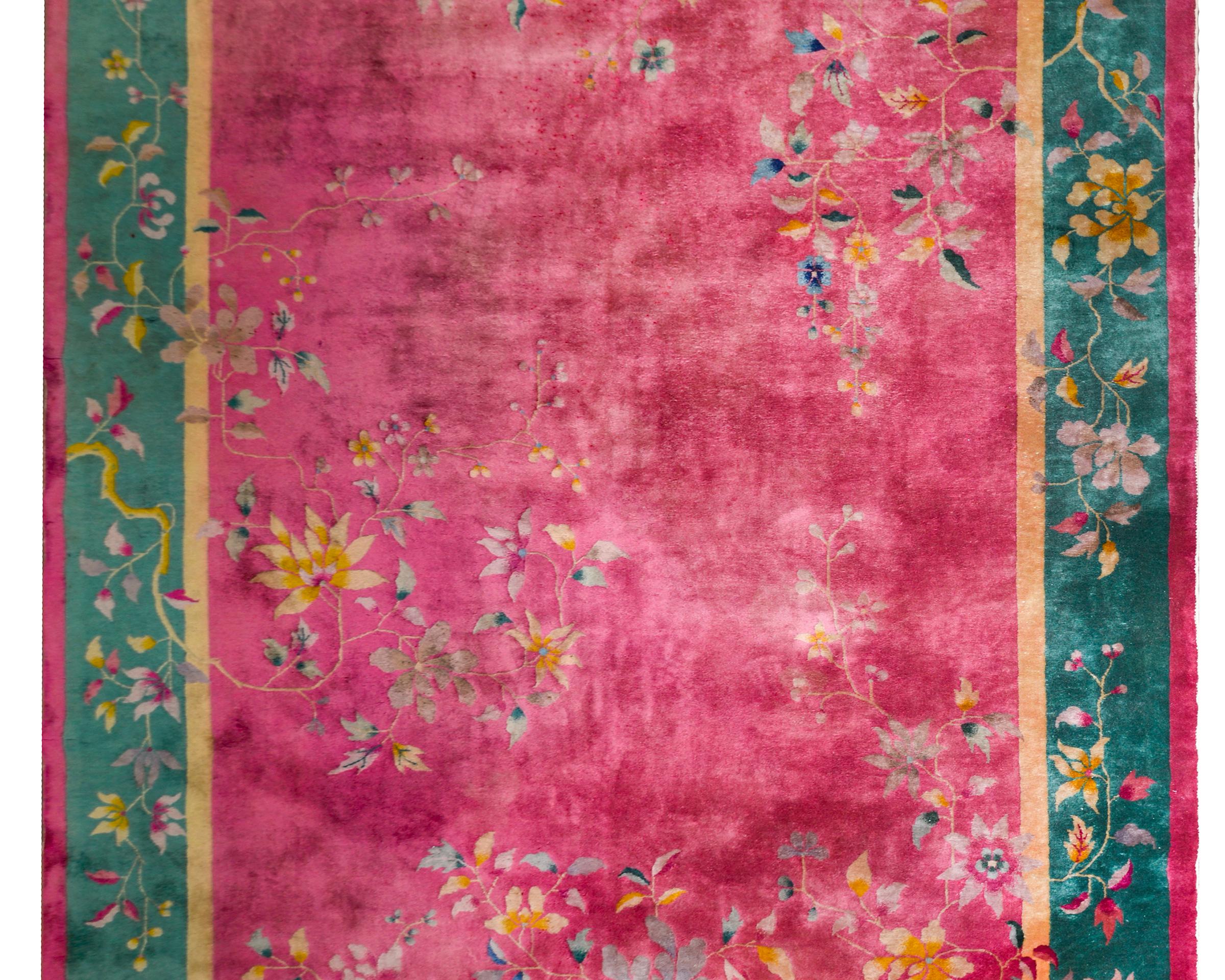 A beautiful early 20th century Chinese Art Deco rug with a brilliant fuchsia field surrounded by a wide turquoise border flanked by narrow gold and fuchsia stripes. Overlaying the border are wonderful large-scale peonies and scrolling vines, all