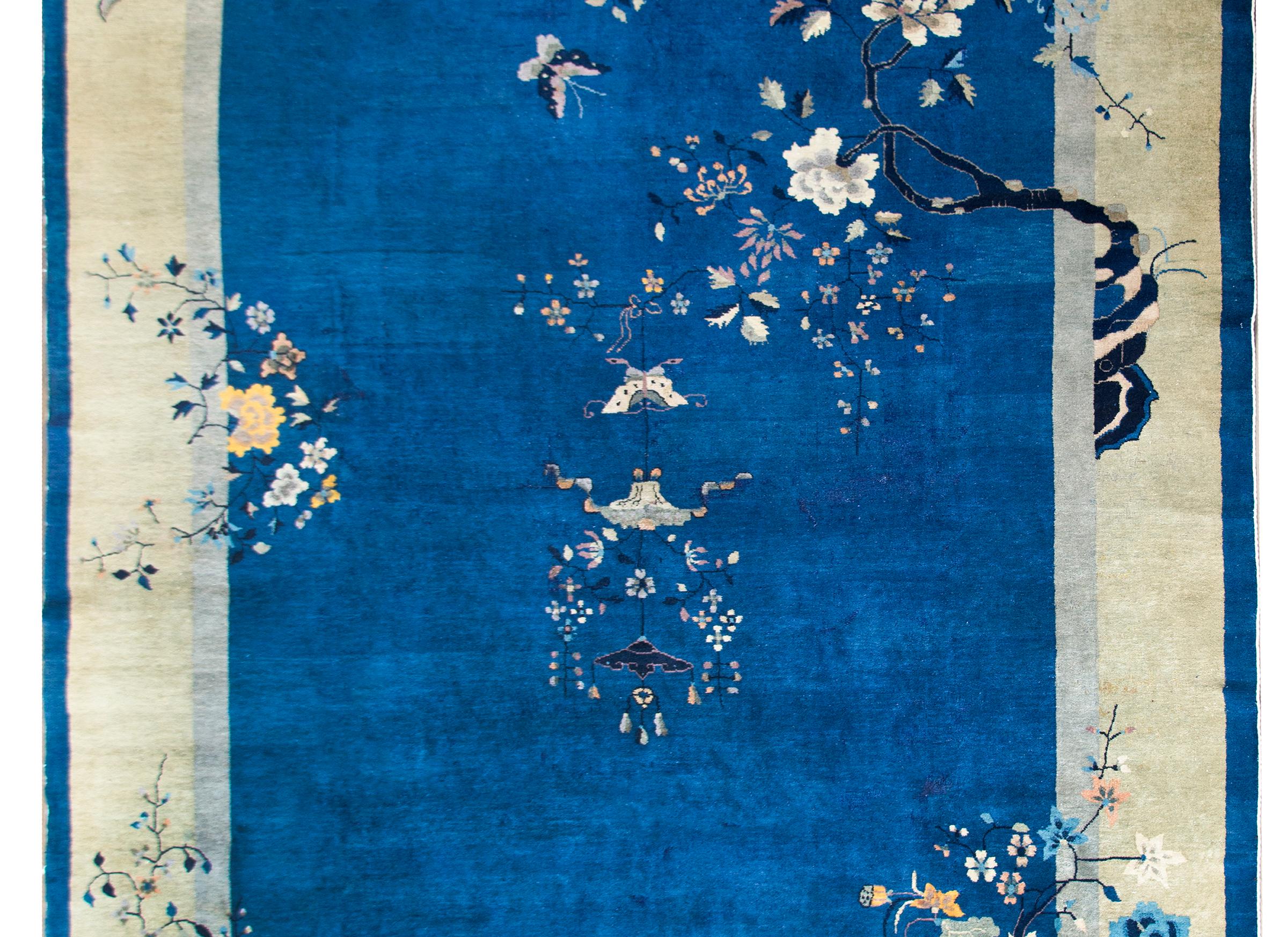 A gorgeous early 20th century Chinese Art Deco rug with a stunning indigo field surrounded by a wide cream and thin gray and indigo borders. Beautifully rendered tree peonies with whips branches are overlaying the field.