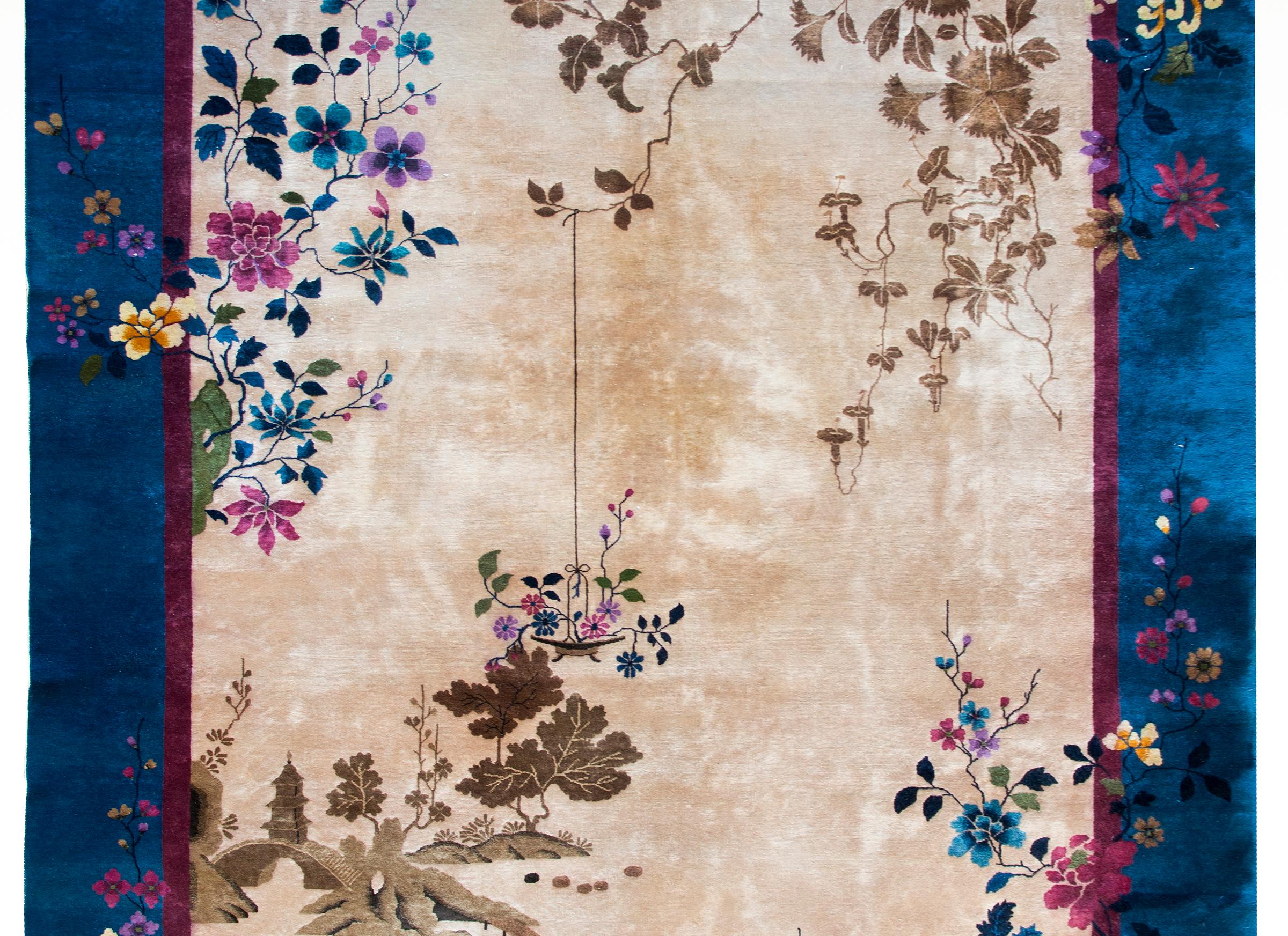 An extraordinary early 20th century Chinese Art Deco rug with a rare grisaille-style field with a tone-on-tone garden scene and surrounded by a brilliant indigo border covered with multi-colored peonies, prunus, and chrysanthemum blossoms.