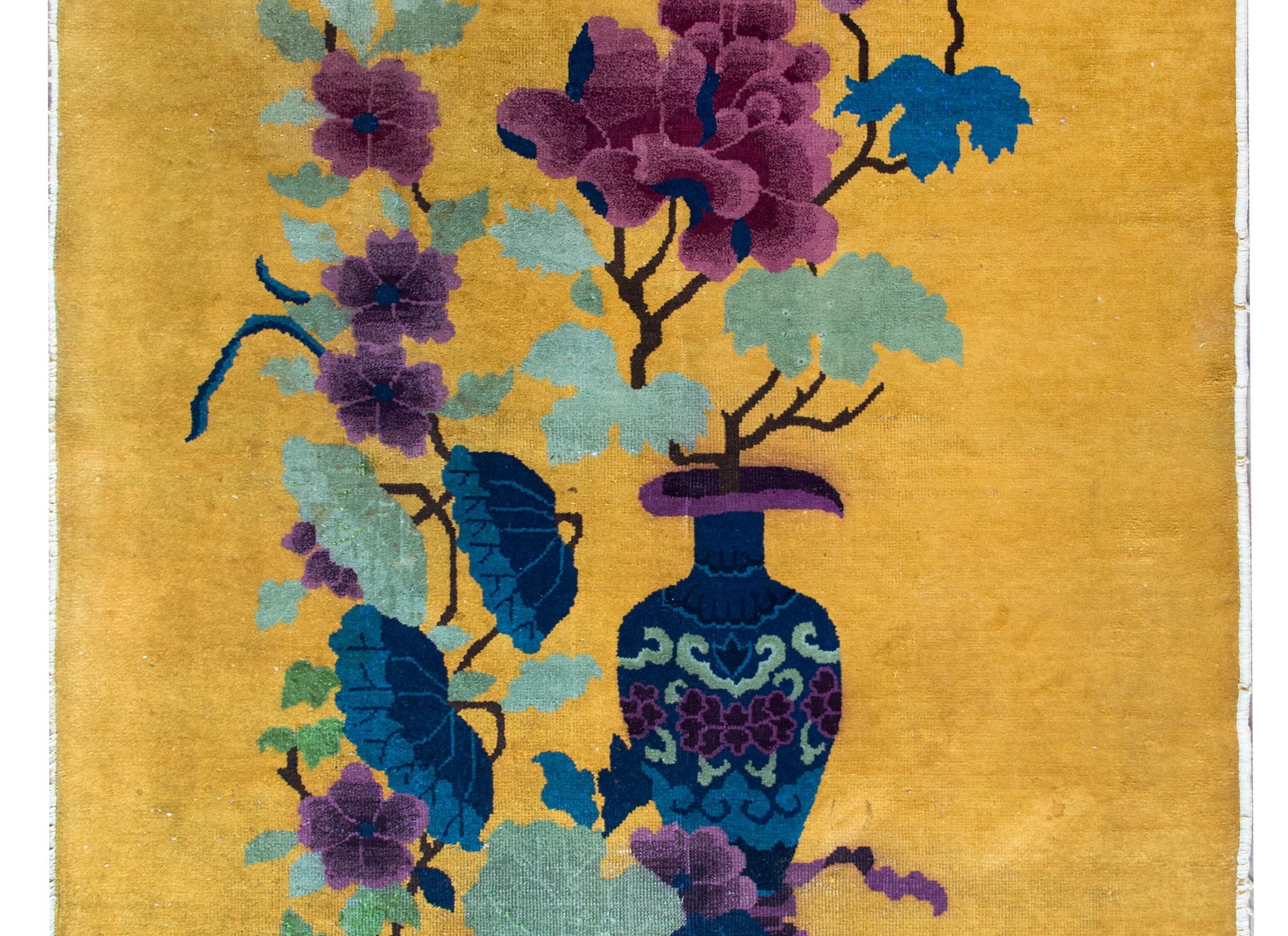 A brilliant early 20th century Chinese Art Deco rug with a wonderful asymmetrical pattern with a vase holding large peony blossoms resting amidst lotus and more peonies, all woven in indigo, green, and varying shades of purple set against a bold
