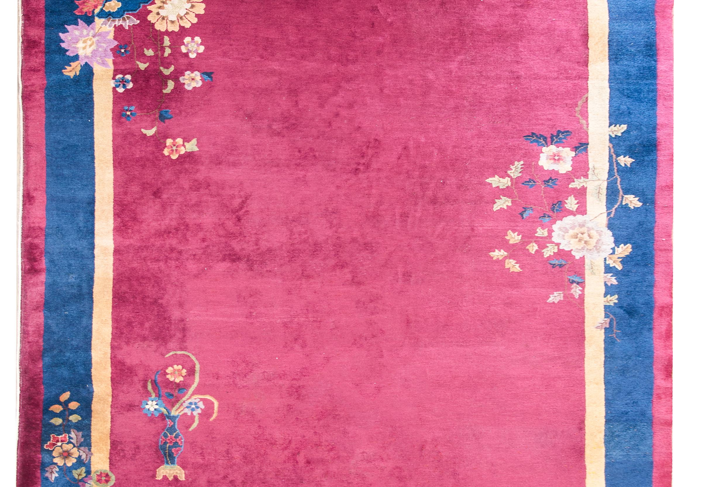 A wonderful early 20th century Chinese Art Deco rug with a cranberry field surrounded by a gold inner stripe, wide indigo central stripe, and a thin cranberry outer stripe. Peony and chrysanthemum clusters dot the field.