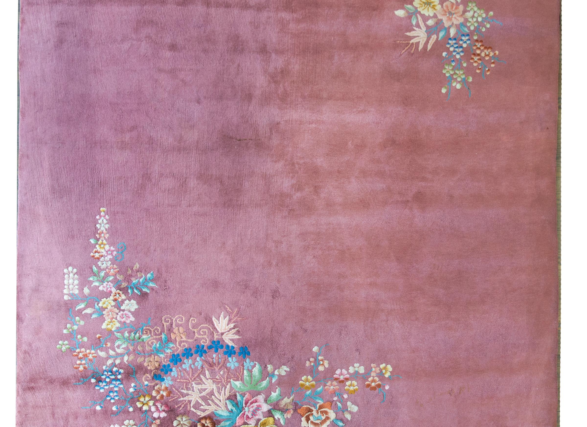 A wonderful early 20th century Chinese Art Deco rug with a solid mauve ground and one large cluster of multi-colored auspicious flowers including peonies, chrysanthemums, and cherry blossoms in one corner, and a smaller version of the same flowers