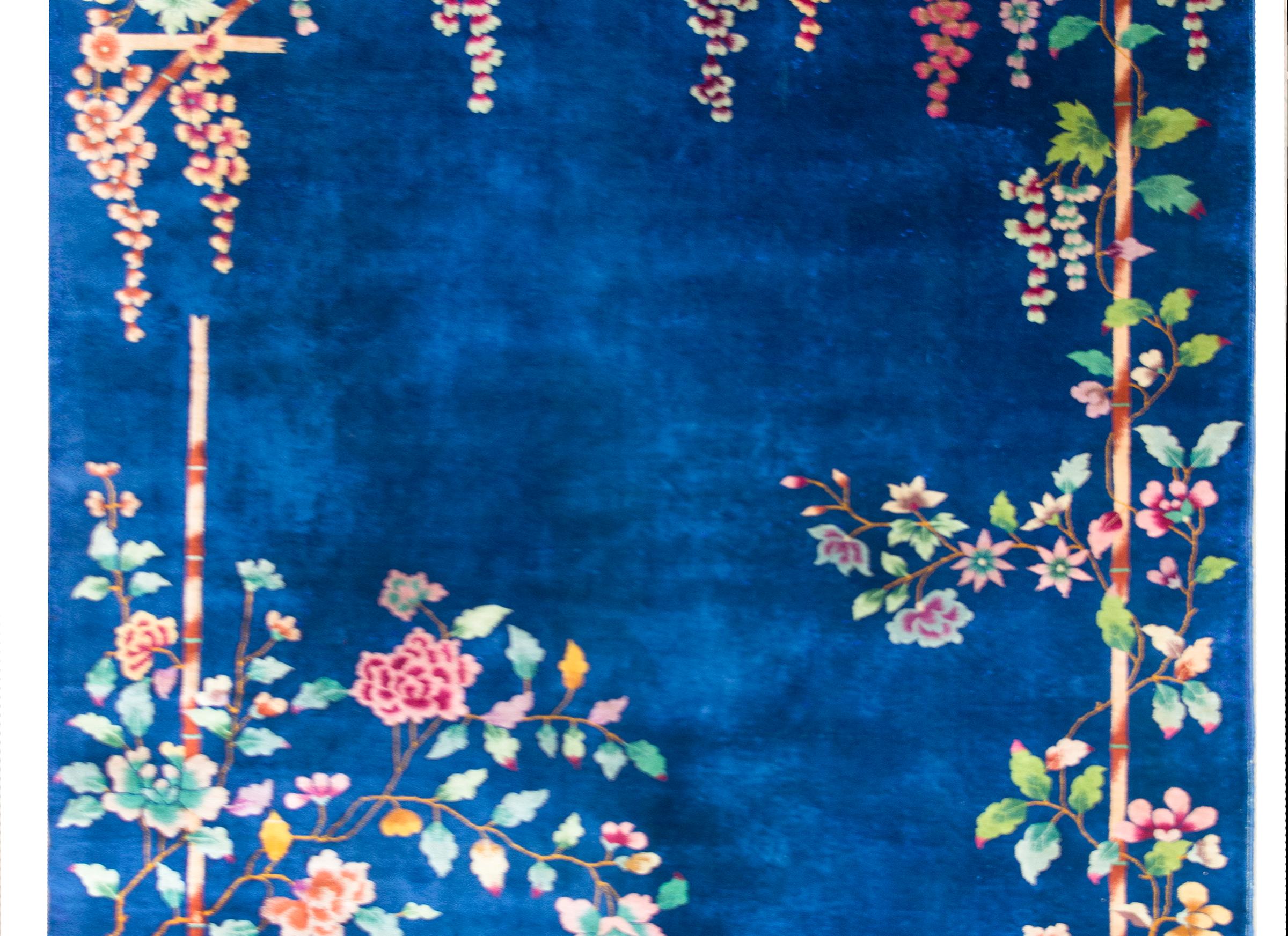 A wonderful early 20th century Chinese Art Deco rug with a brilliant indigo field overlaid with a multi-colored peonies and billowing flower clusters hanging from a bamboo trellis.
