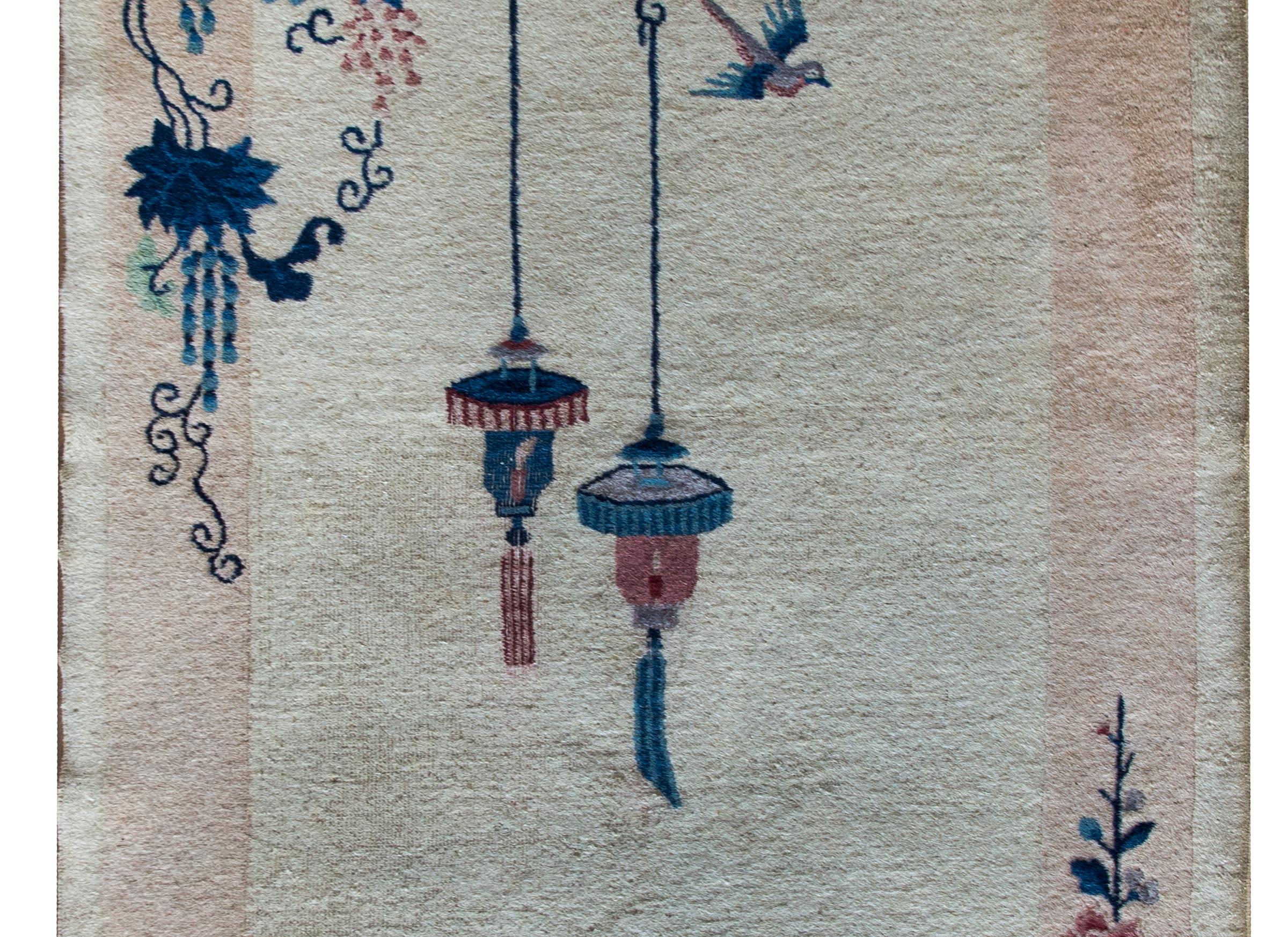A quiet yet sophisticated early 20th century Chinese Art Deco rug with a gray background surrounded by a wide pale pink border, and overlaid with a pair of lanterns hanging from a flowering wisteria vine in one corner, and a vase potted with a