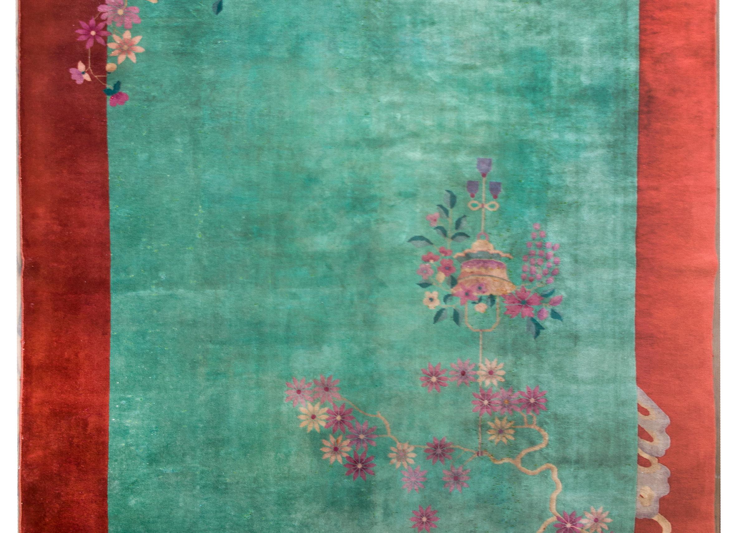 A gorgeous early 20th century Chinese Art Deco rug with a mint green field surrounded by a wide burnt orange border, and all overlaid with multicolored prunus blossoms and peonies.  