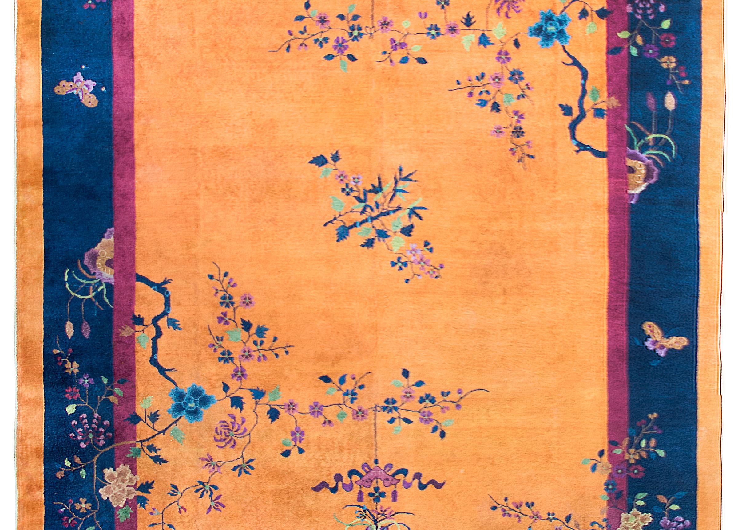 A fantastic early 20th century Chinese Art Deco rug with a brilliant orange sherbet field surrounded by a thin violet liner strip and a wide indigo outer stripe, and all overlaid with vases potted with multicolored peonies in opposing corners, and