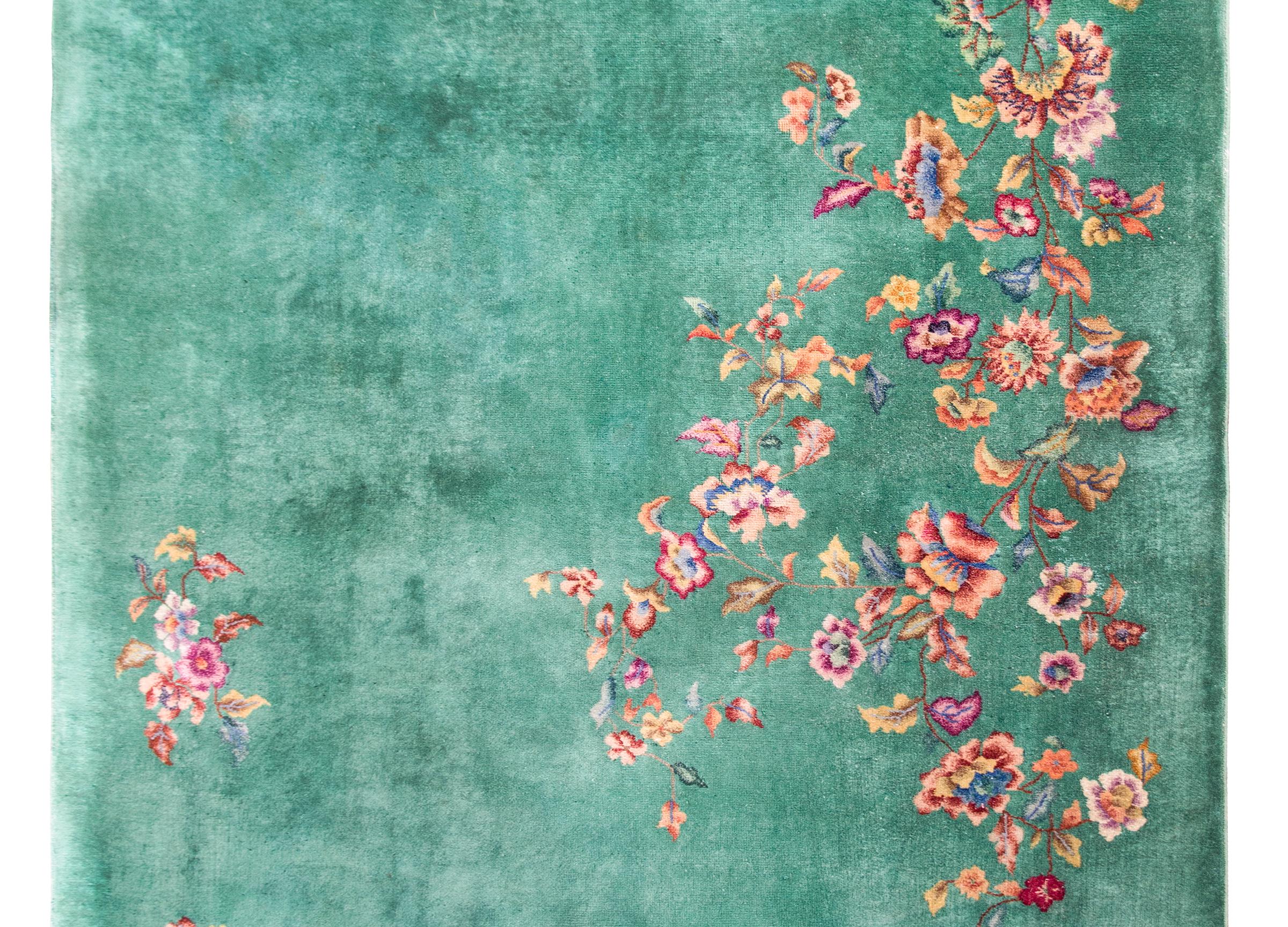 A beautiful early 20th century Chinese Art Deco rug with an all-over celadon green field overlaid with multi-colored peonies, chrysanthemum, lotus, and cherry blossoms, all auspicious symbols of the four seasons.