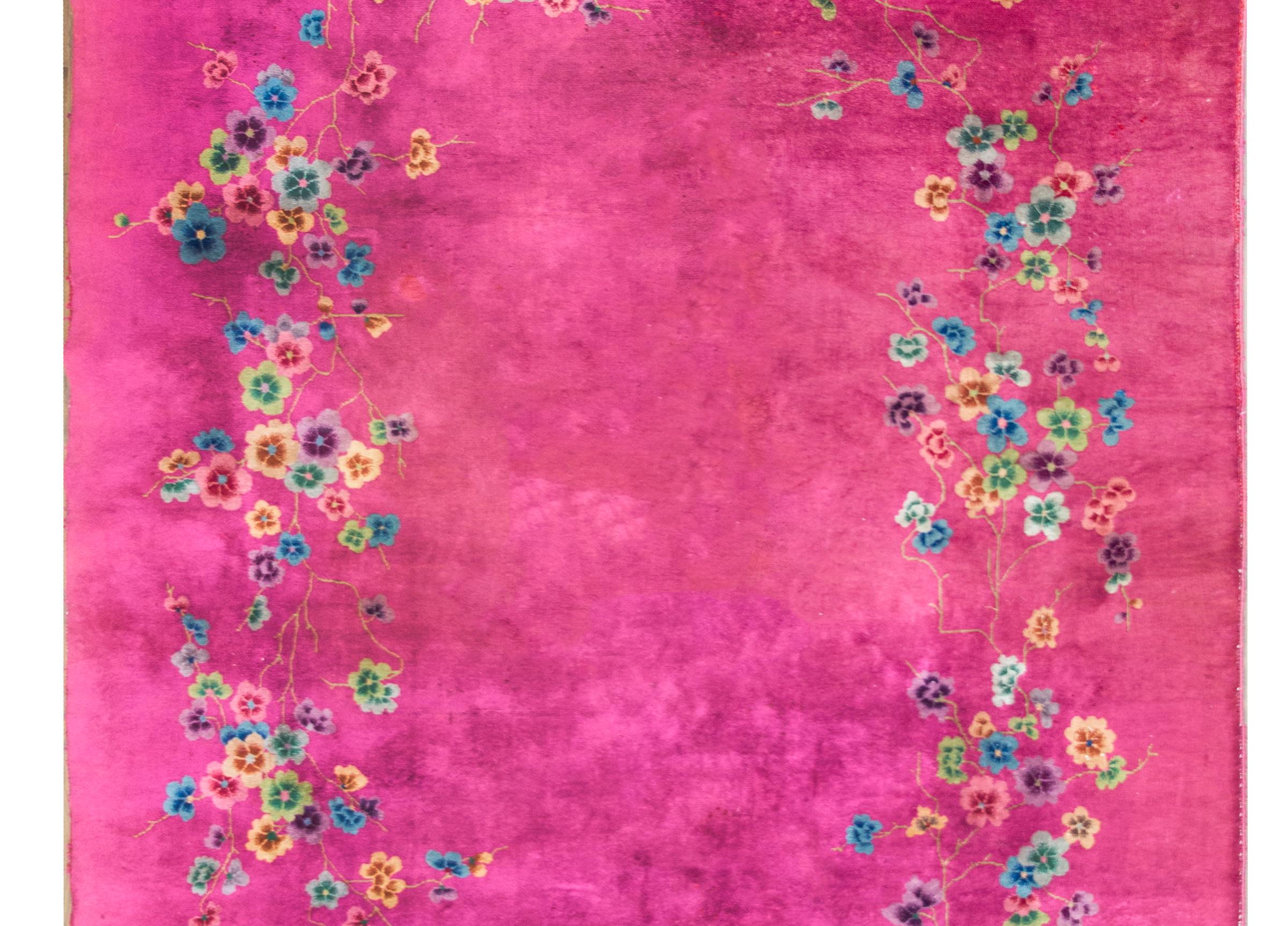 An incredible early 20th century Chinese Art Deco rug with a fucshia ground overlaid with multi-colored flowers and scrolling vines, all woven in pinks, golds, greens, violets, and indigos.  