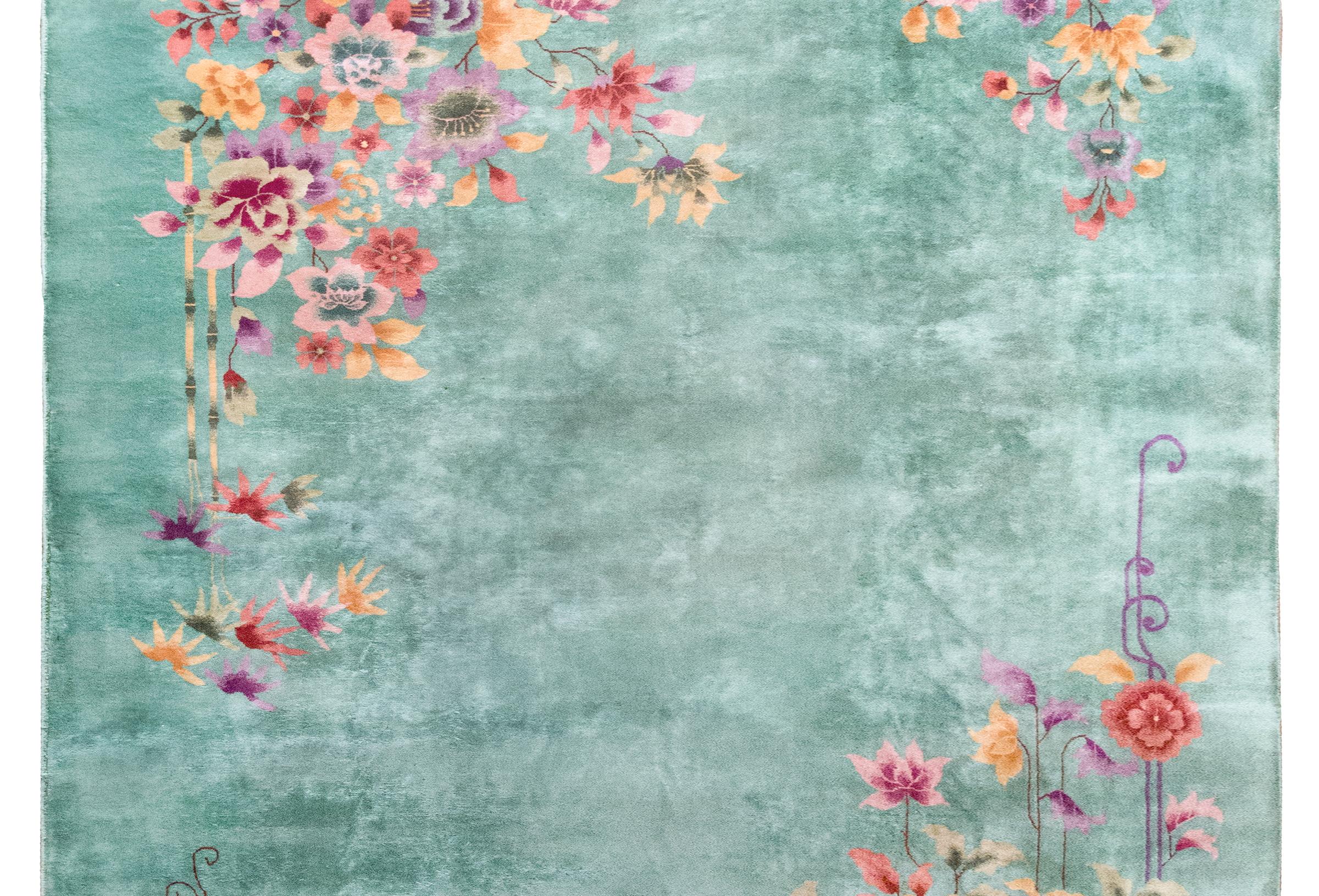 Un audacieux et magnifique tapis chinois Art déco du début du 20e siècle avec un champ vert menthe avec de grandes grappes de fleurs de bon augure, dont des pivoines et des chrysanthèmes, le tout tissé dans des oranges, des roses, des verts, des