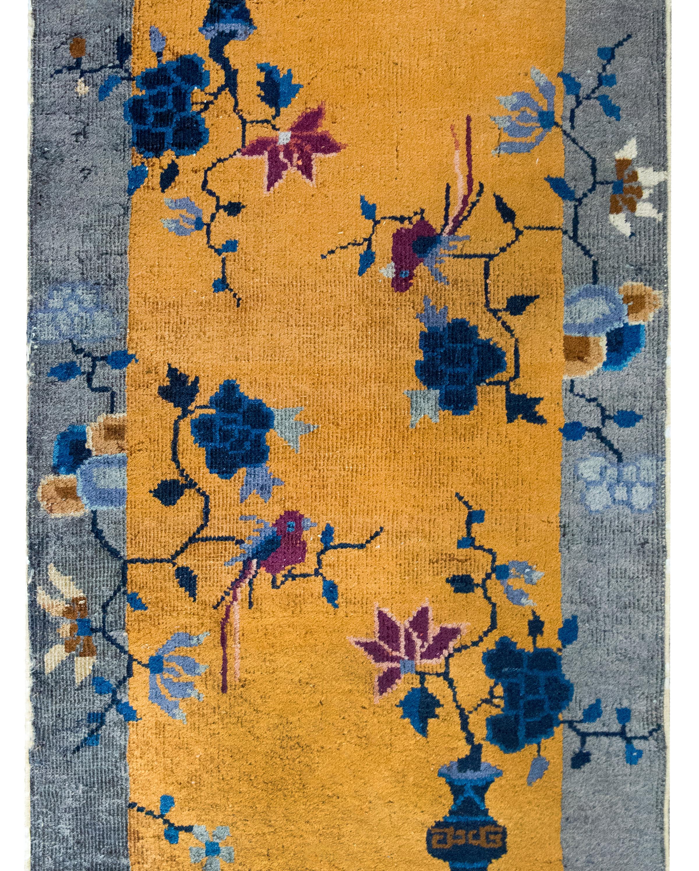 A wonderful early 20th century Chinese Art Deco rug featuring a gold field surrounded by a wide gray border, and all overlaid with vases potted with violet and light and dark indigo chrysanthemums, peonies, and lotus flowers in alternating corners.