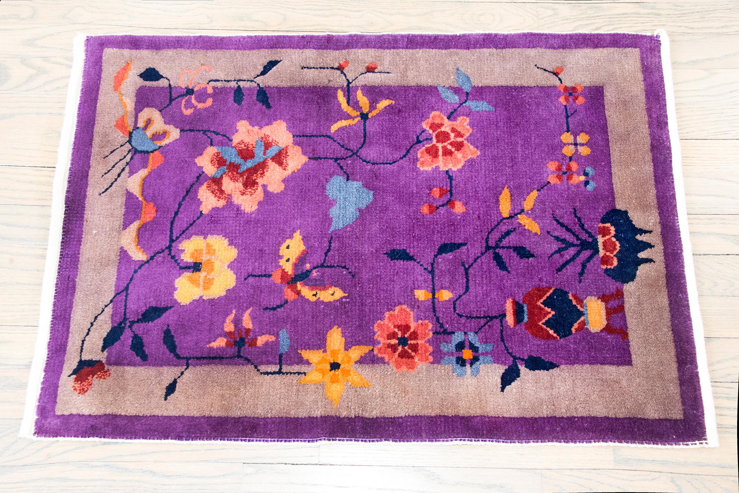 Tapis chinois Art déco du début du XXe siècle, avec un champ violet entouré d'une large bordure grise, et recouvert d'un buisson de pivoines en pot, le tout tissé dans des tons variés d'indigo, de corail, de rose et d'or.