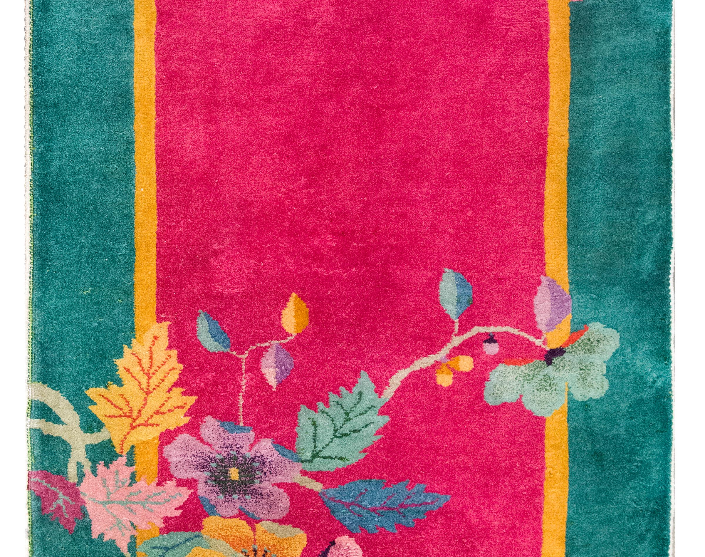 An early 20th century Chinese Art Deco rug with a fuchsia field surrounded by a thin gold and wide turquoise border, and overlaid with lotus flowers and leaves in one corner, ducks in another, and cherry blossoms at the top, and all woven in varying