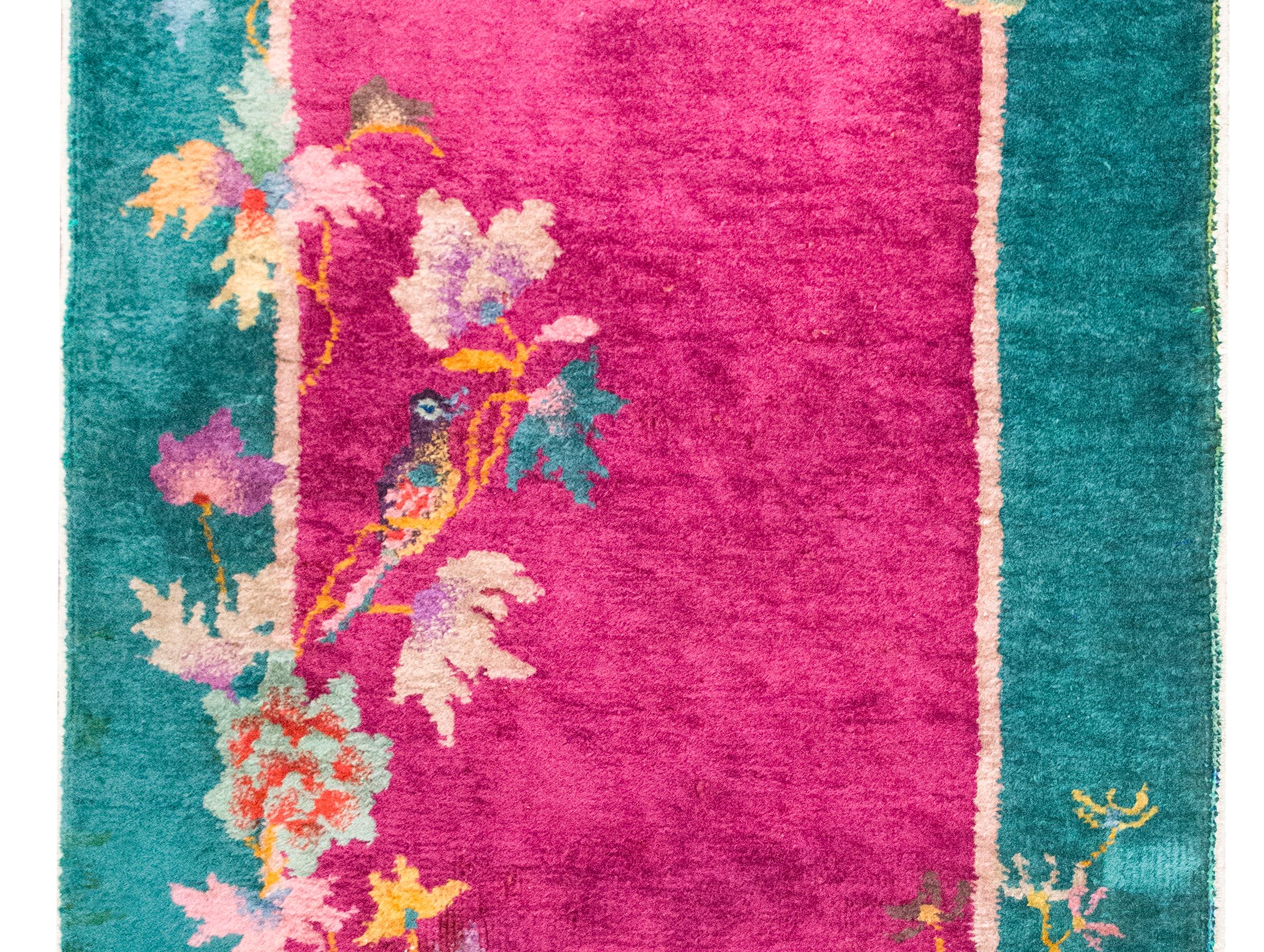 A wonderful early 20th century Chinese Art Deco rug with a fuchsia field surrounded by a wide turquoise border, and all overlaid with multi-colored flowers including lotus, chrysanthemum, peonies, and cherry blossoms, and all woven in varying shades