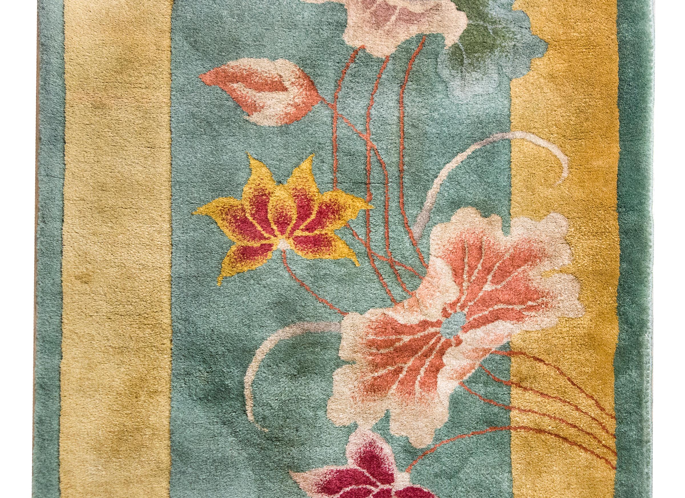 A beautiful early 20th century Chinese Art Deco rug with a pale mint green field surrounded by a wide yellow border, and overlaid with multi-colored lotus flowers and leaves, woven in varying shades of pink, coral, gold, green, and indigo.