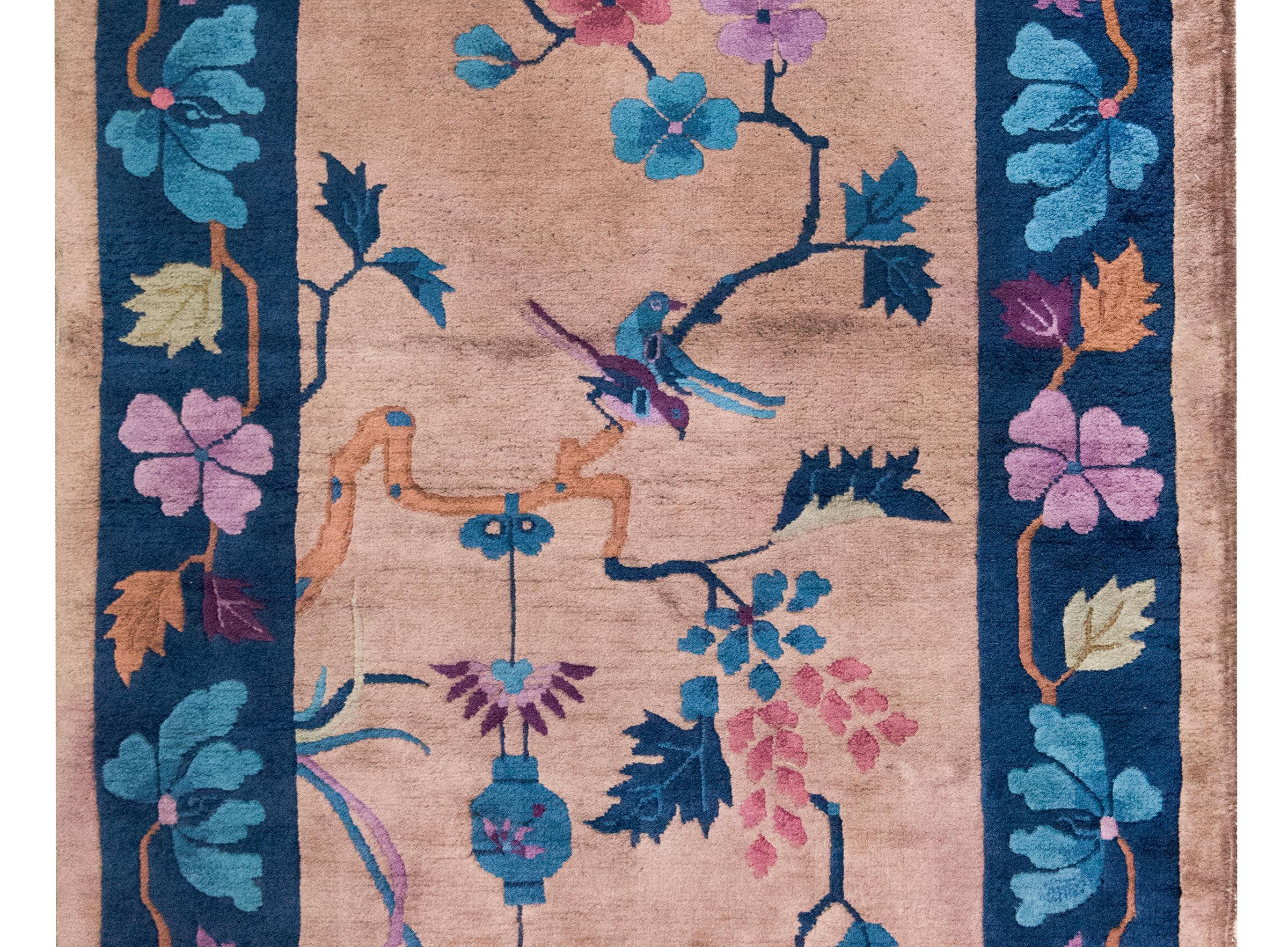 Tapis chinois Art déco du début du XXe siècle, magnifiquement tissé avec un motif lyrique et symbolique. En son centre, une branche de cerisier gracieusement torsadée s'étend à travers le champ, ornée de délicates fleurs roses et lavande. Deux pies