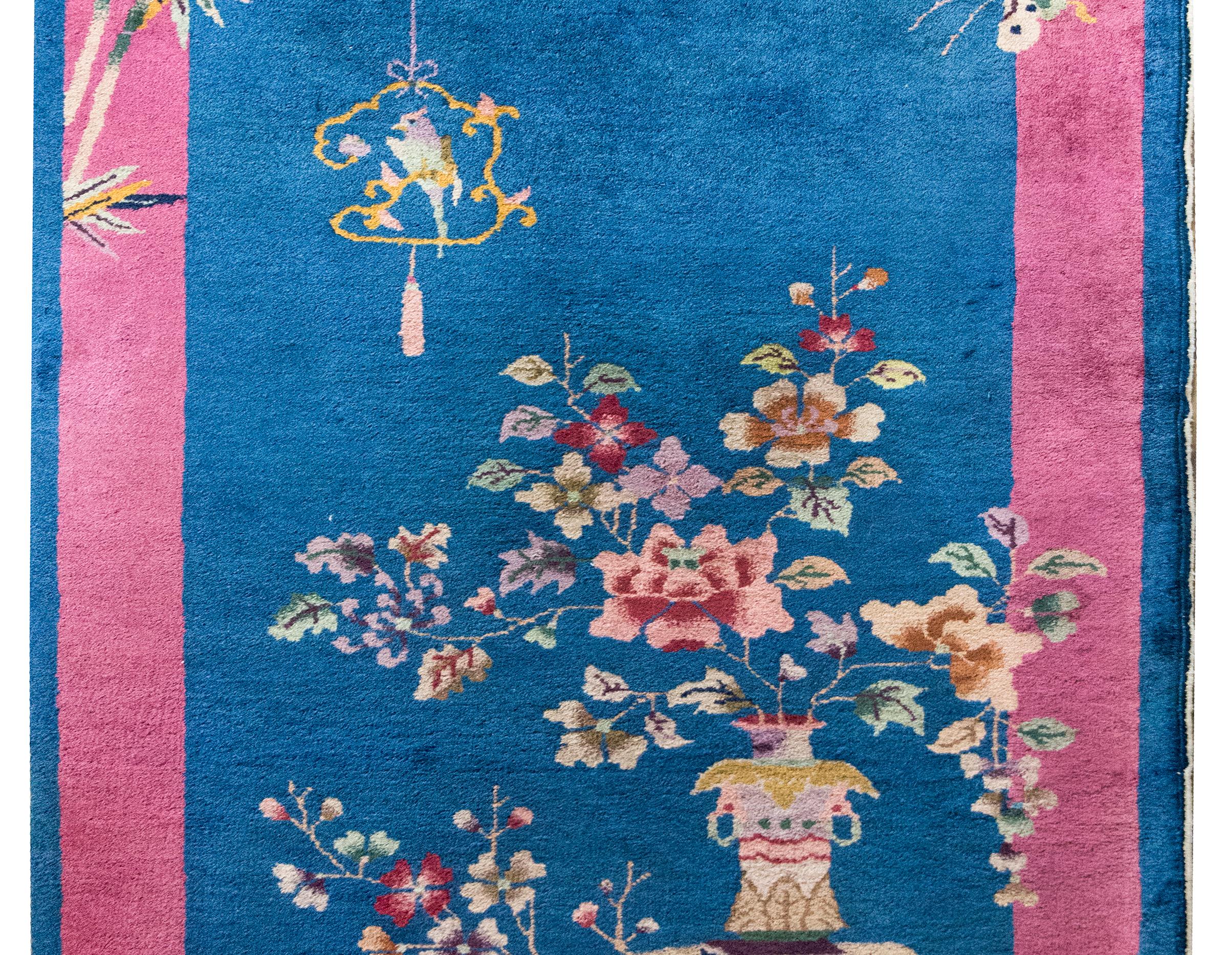 A stunning example of early 20th-century Chinese Art Deco weaving, this rug features a deep navy blue field framed by a wide violet border, creating a dramatic contrast that enhances its intricate design. Scattered across the surface are scholar’s