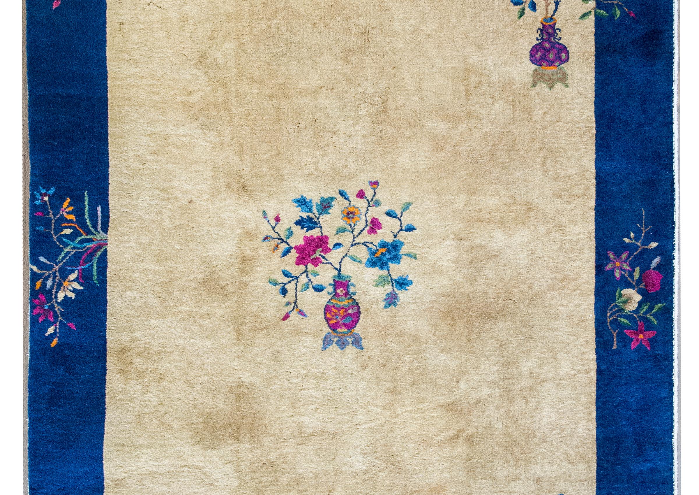 Esta alfombra china Art Déco, tejida en la década de 1920, es un ejemplo radiante de una interpretación exclusivamente china del movimiento Art Déco. Sobre un suave campo color champán y enmarcada por un amplio borde añil, la composición equilibra