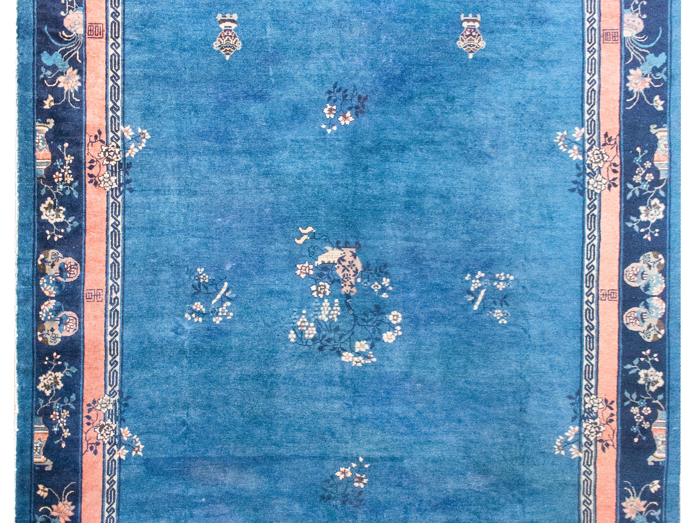 This early 20th-century Chinese Art Deco rug features a deep indigo field that draws you in immediately. Around it, several borders add layers of interest: one with a continuous meandering motif, another a slender salmon stripe, and a third