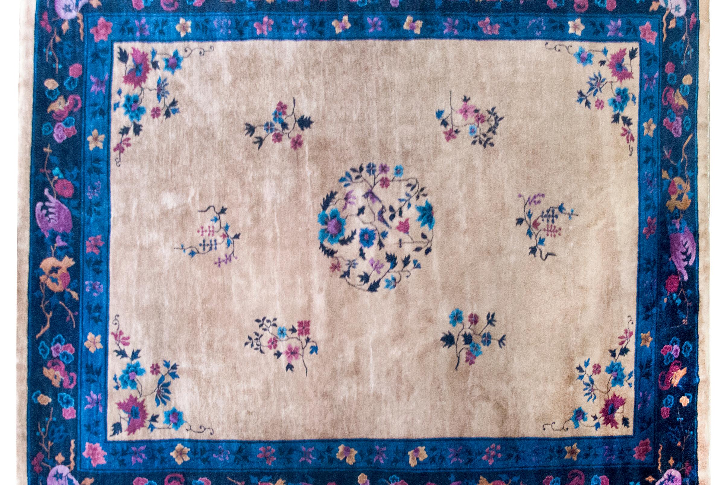 A lush and lyrical composition, this early 20th-century Chinese Art Deco rug brings together bold color, cultural symbolism, and painterly design. At its center, a floral medallion blossoms with peonies, chrysanthemums, and cherry