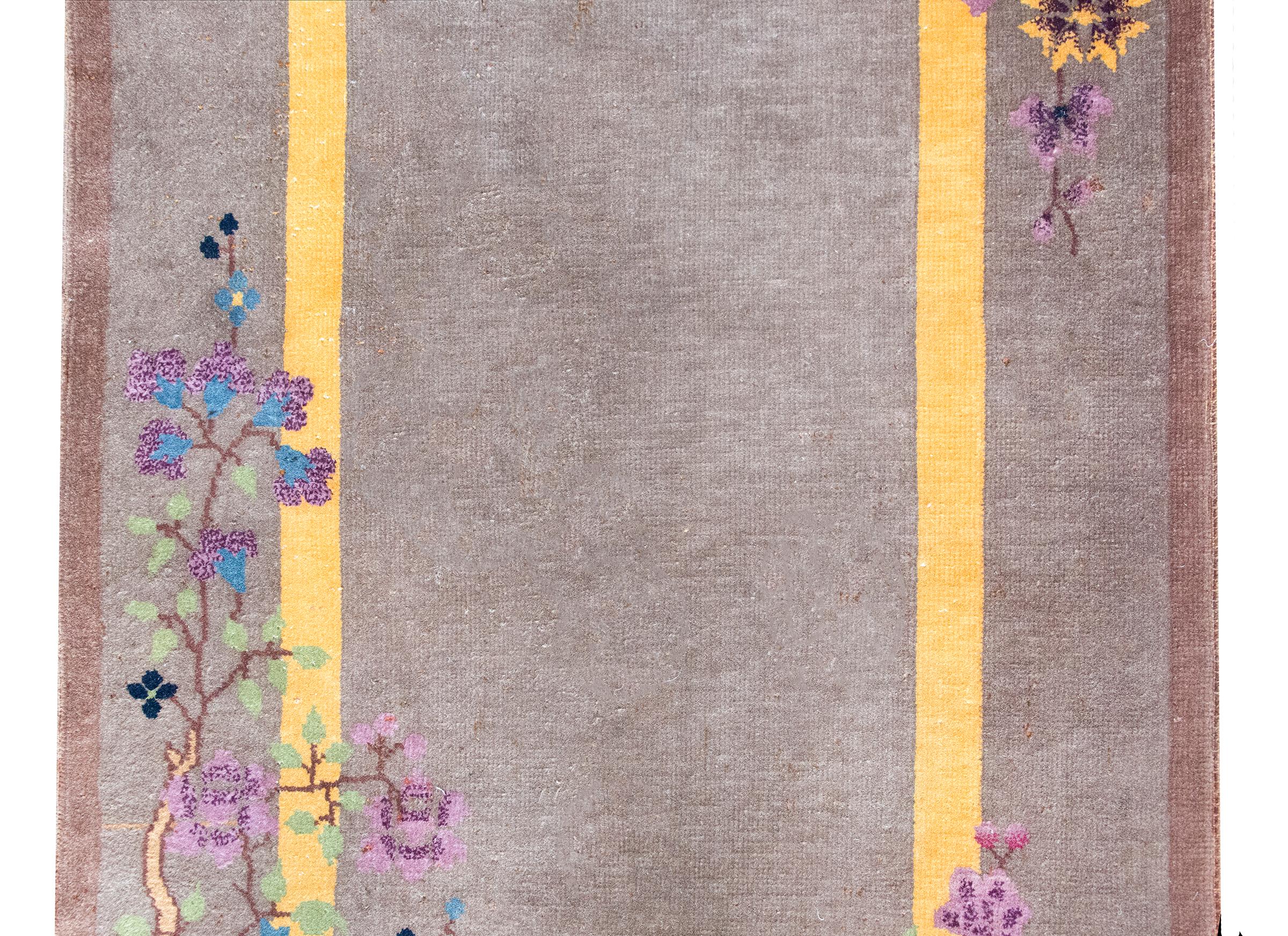 Ce tapis chinois Art déco du début du XXe siècle est un exemple raffiné de la rencontre entre l'Orient et l'Occident, avec une palette calme et un symbolisme riche. Le champ est d'un gris doux et élégant, encadré par une étroite bande intérieure