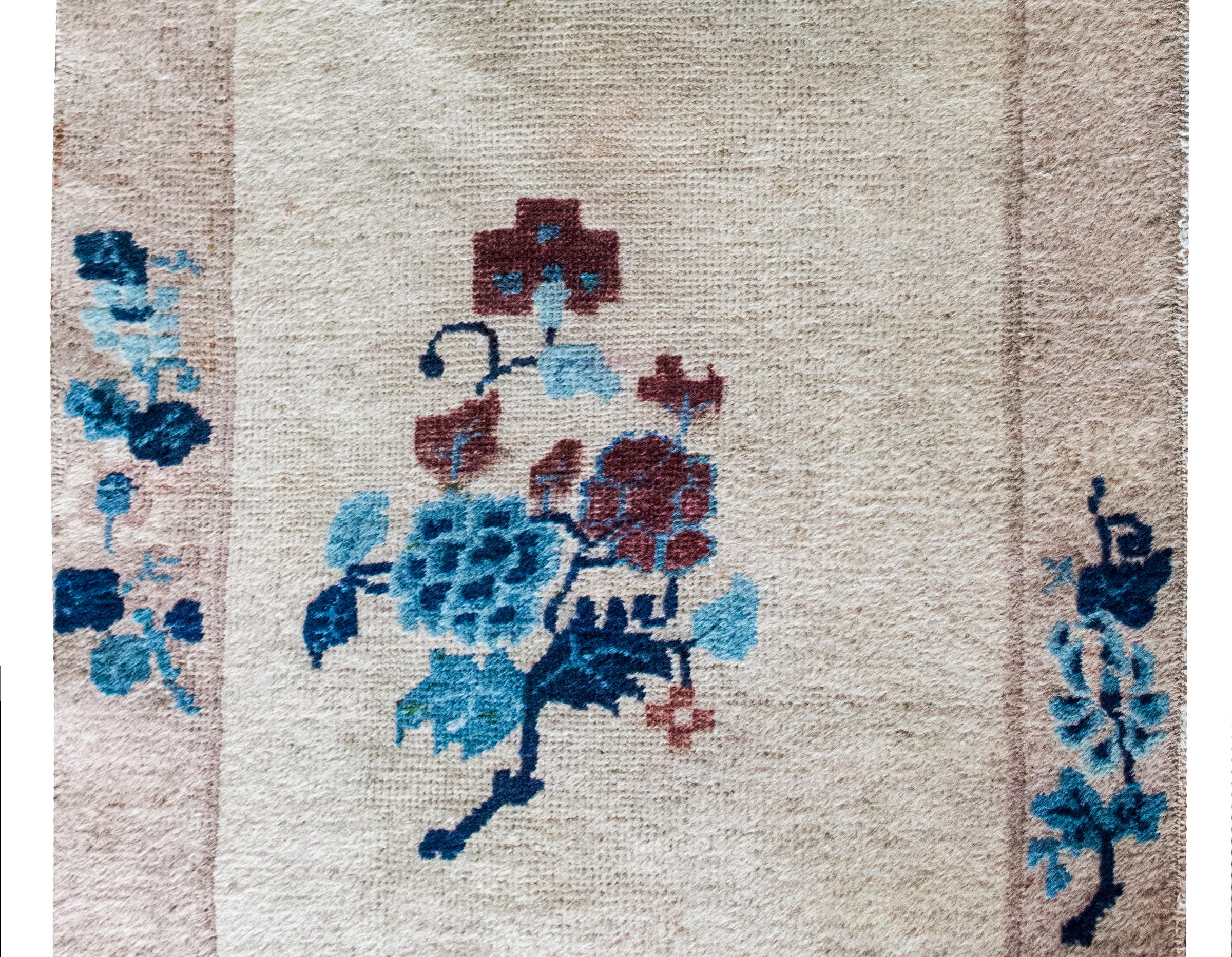 Ce tapis chinois Art déco du début du XXe siècle est une étude discrètement dramatique de l'élégance et de l'asymétrie. Le champ gris doux est ancré par un grand médaillon décentré - une grappe luxuriante de pivoines rendues dans des tons lunatiques