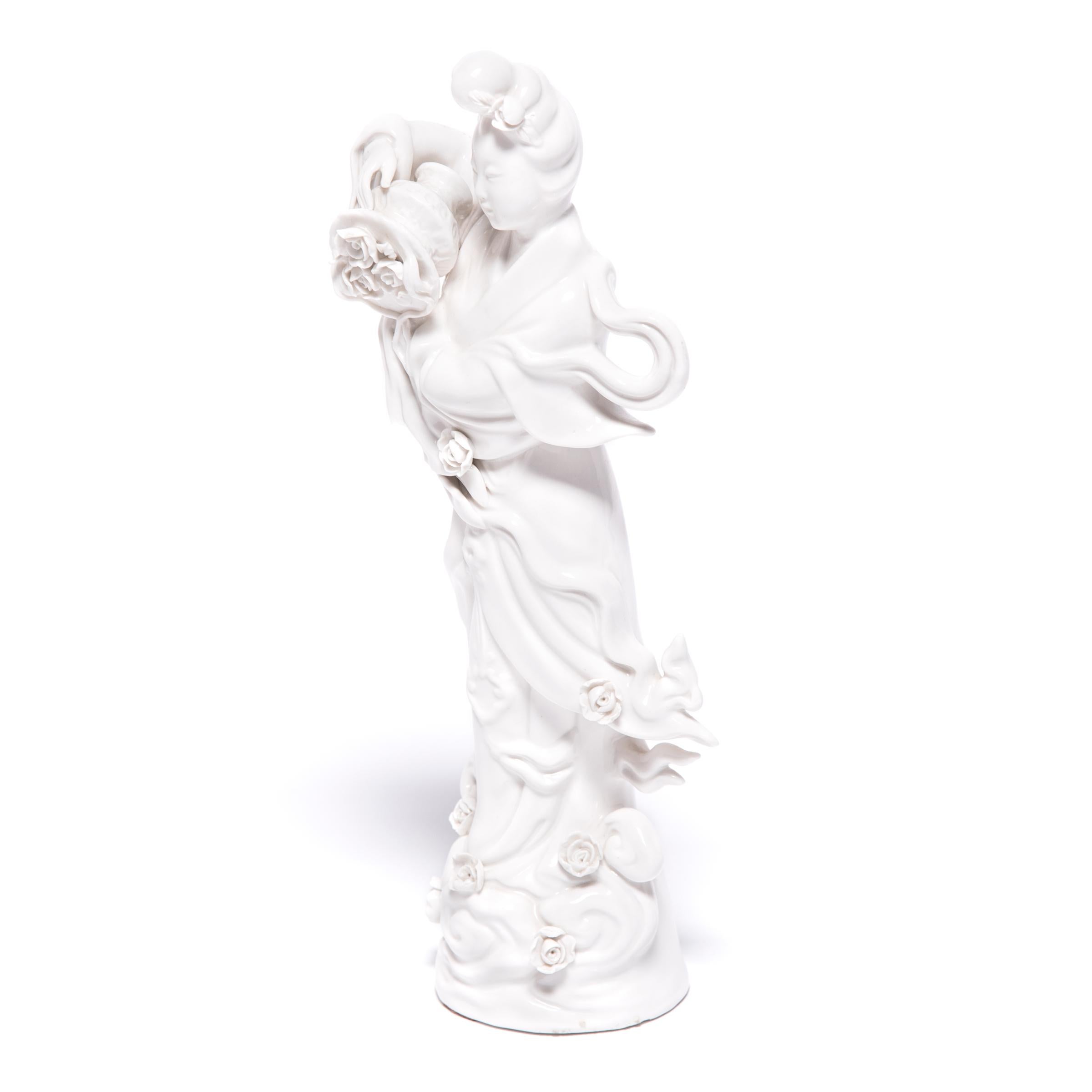 A symbol of compassion and wisdom, Guan Yin is a bodhisattva venerated by Buddhists and Taoists alike. This exquisite porcelain sculpture from circa 1900 depicts the serene-faced goddess spilling roses from a basket, with blossoms cascading down her