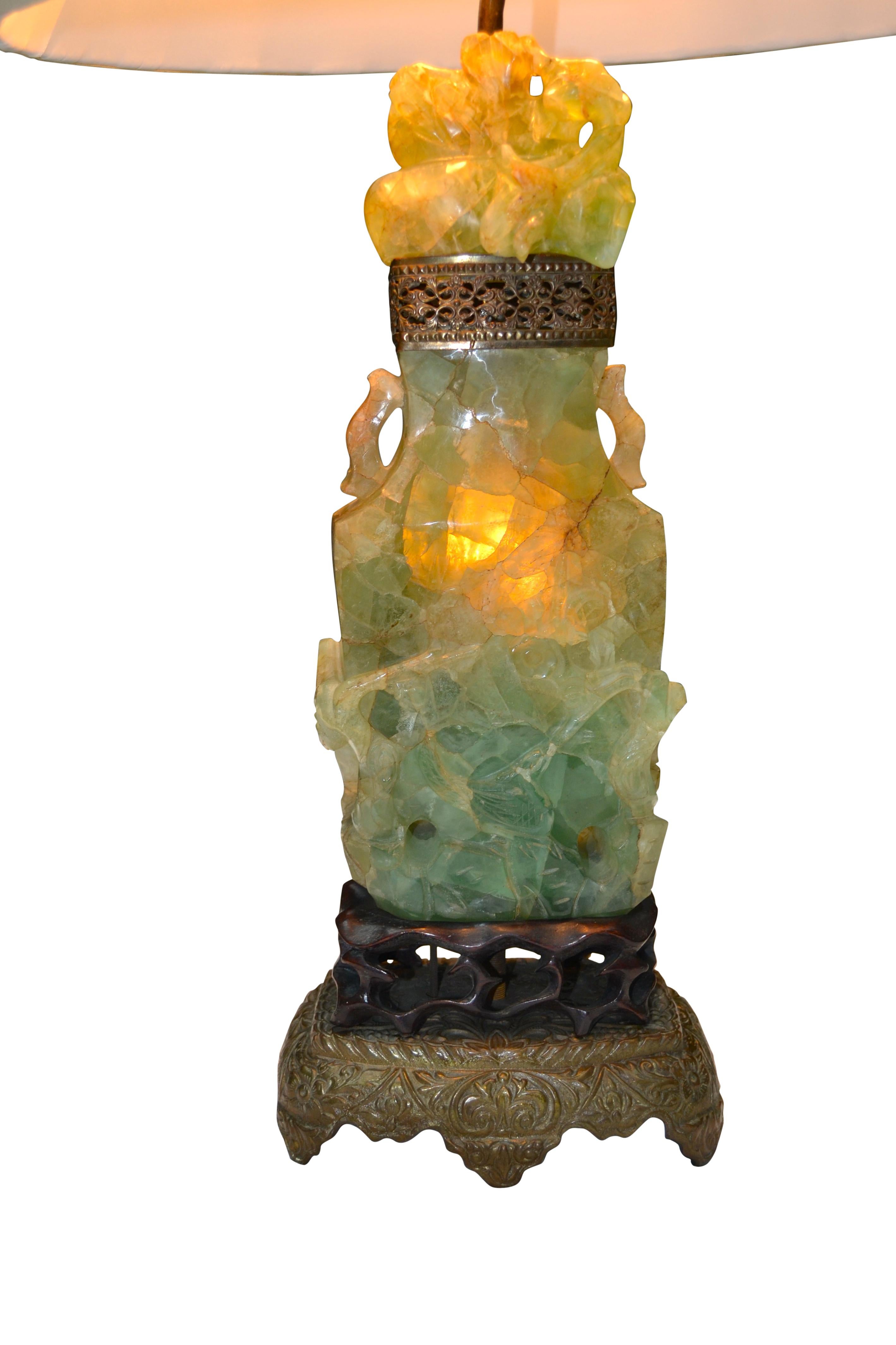 A Chinese carved stone lamp mounted on a brass and a carved rosewood base. The carved stone is often referred to as Jadeite or Quartz but is in fact from the fluorite family. This lamp base was carved in China and exported to the United States