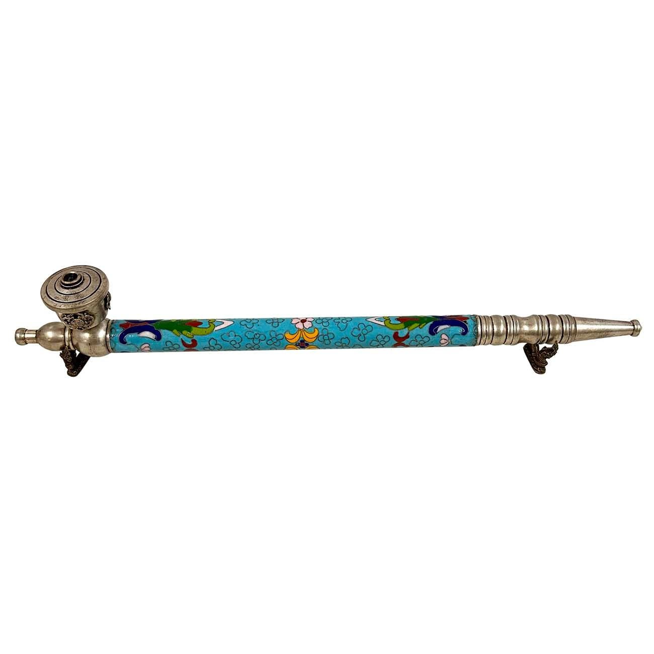 This Chinese Cloisonne smoking pipe features a long, slender stem decorated with colorful cloisonné enamel, a technique involving colored-glass paste placed within metal enclosures. The pipe also includes silver fittings at both ends and a bowl at