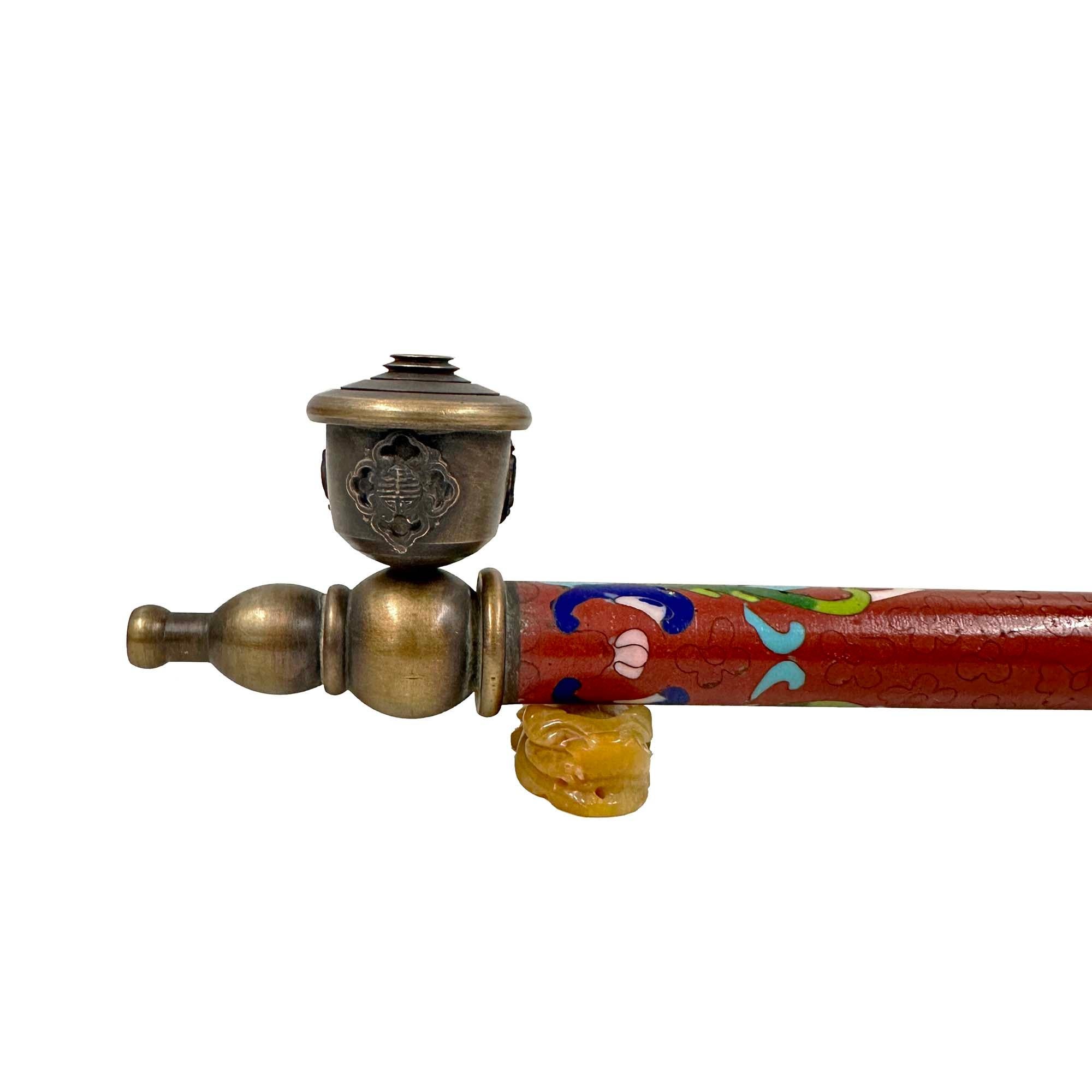 This Chinese Cloisonne smoking pipe features a long, slender stem decorated with colorful cloisonné enamel, a technique involving colored-glass paste placed within metal enclosures. The pipe also includes silver fittings at both ends and a bowl at