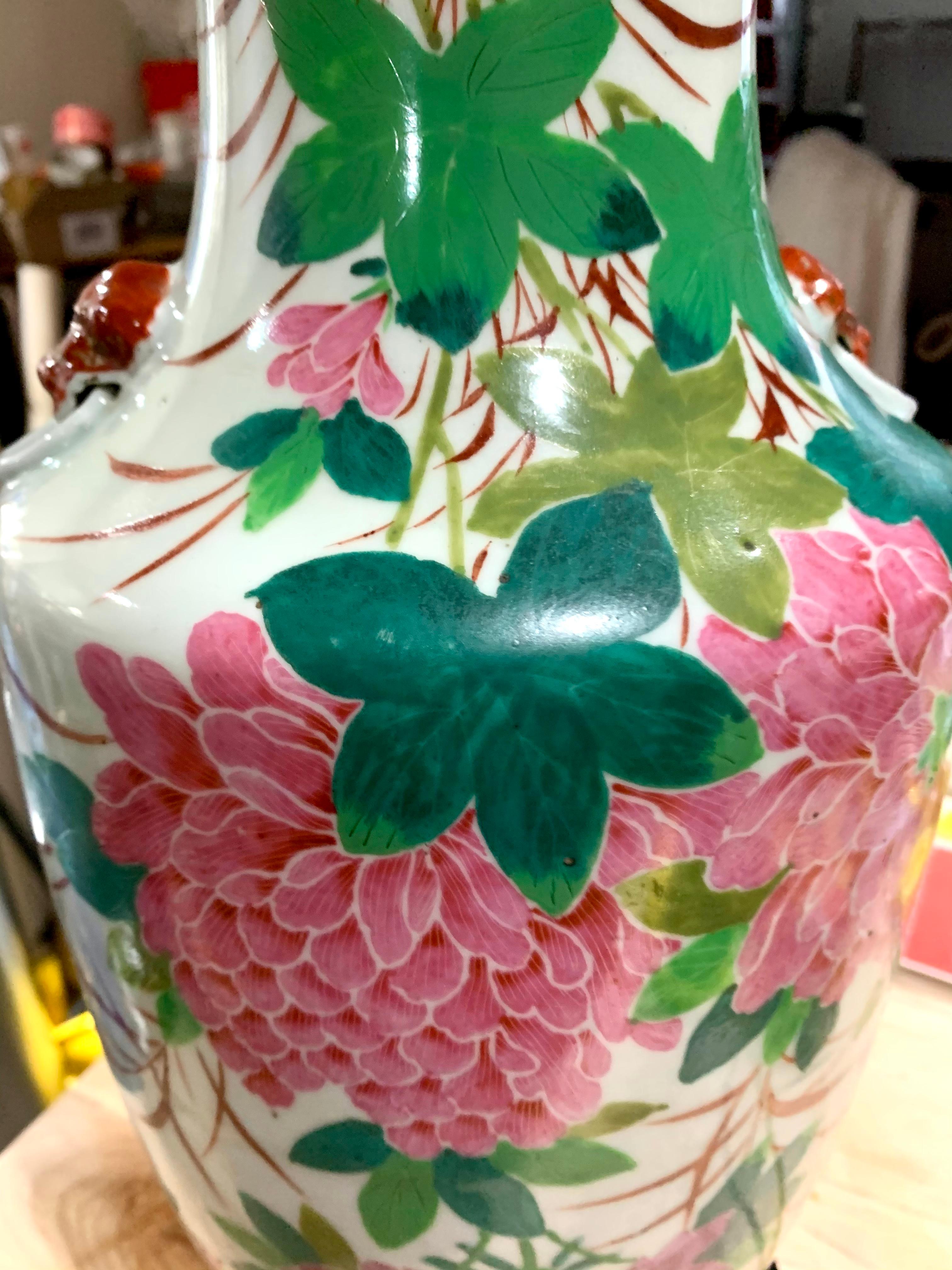 Chinese Deco Chrysanthemum Porcelain Lamp, Hollywood Regency, Early 20th Century.   Hand painted. Floral front, lion handles and calligraphy on back. This listing is for a single table lamp. No lampshade. Measurement to top of socket approx. 21”.