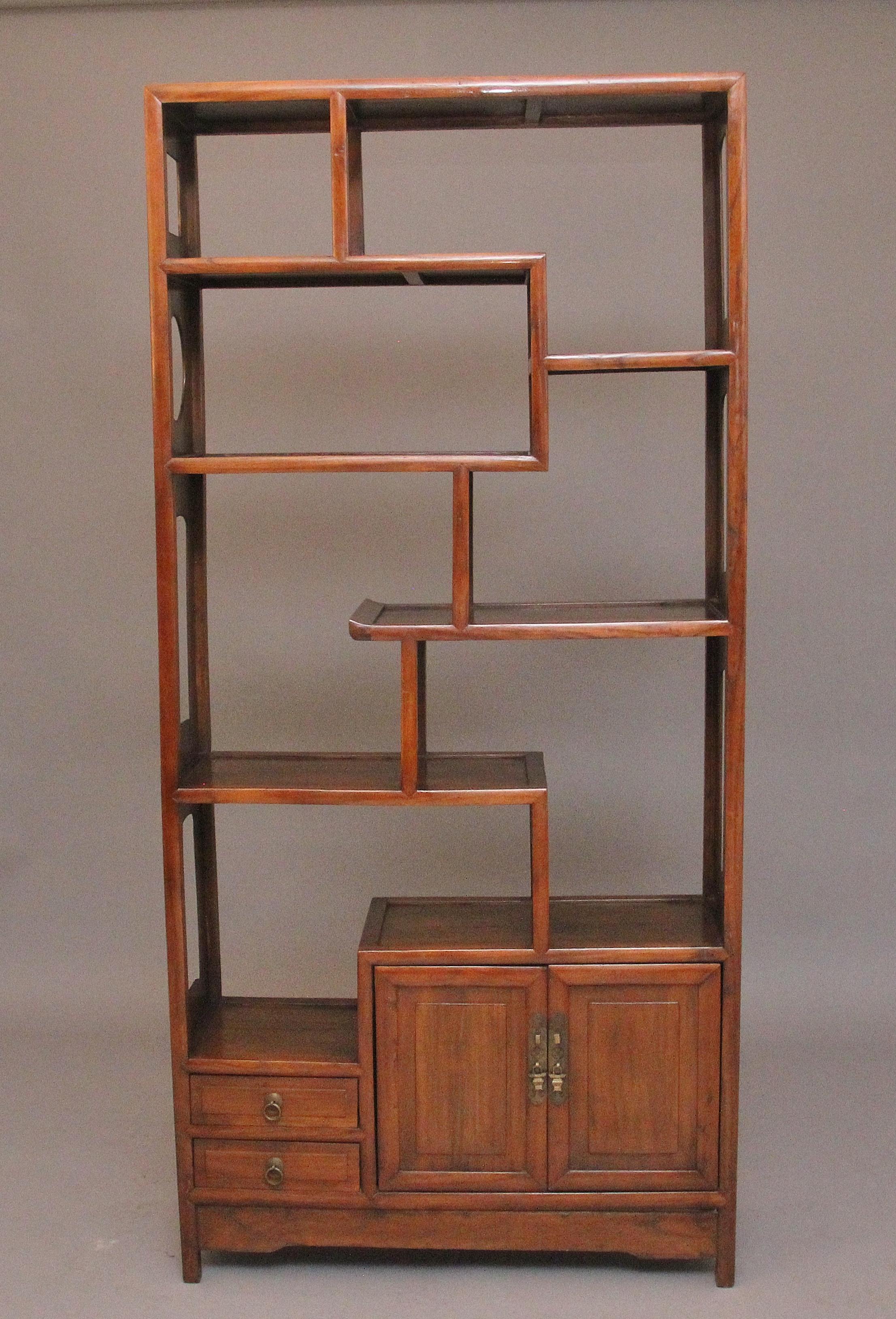 Vitrine chinoise en bois dur du début du 20e siècle, avec un bel agencement d'étagères, des armoires et des tiroirs en dessous, des objets en laiton d'origine, les côtés de la vitrine ayant des découpes décoratives.  Idéale pour exposer des objets,