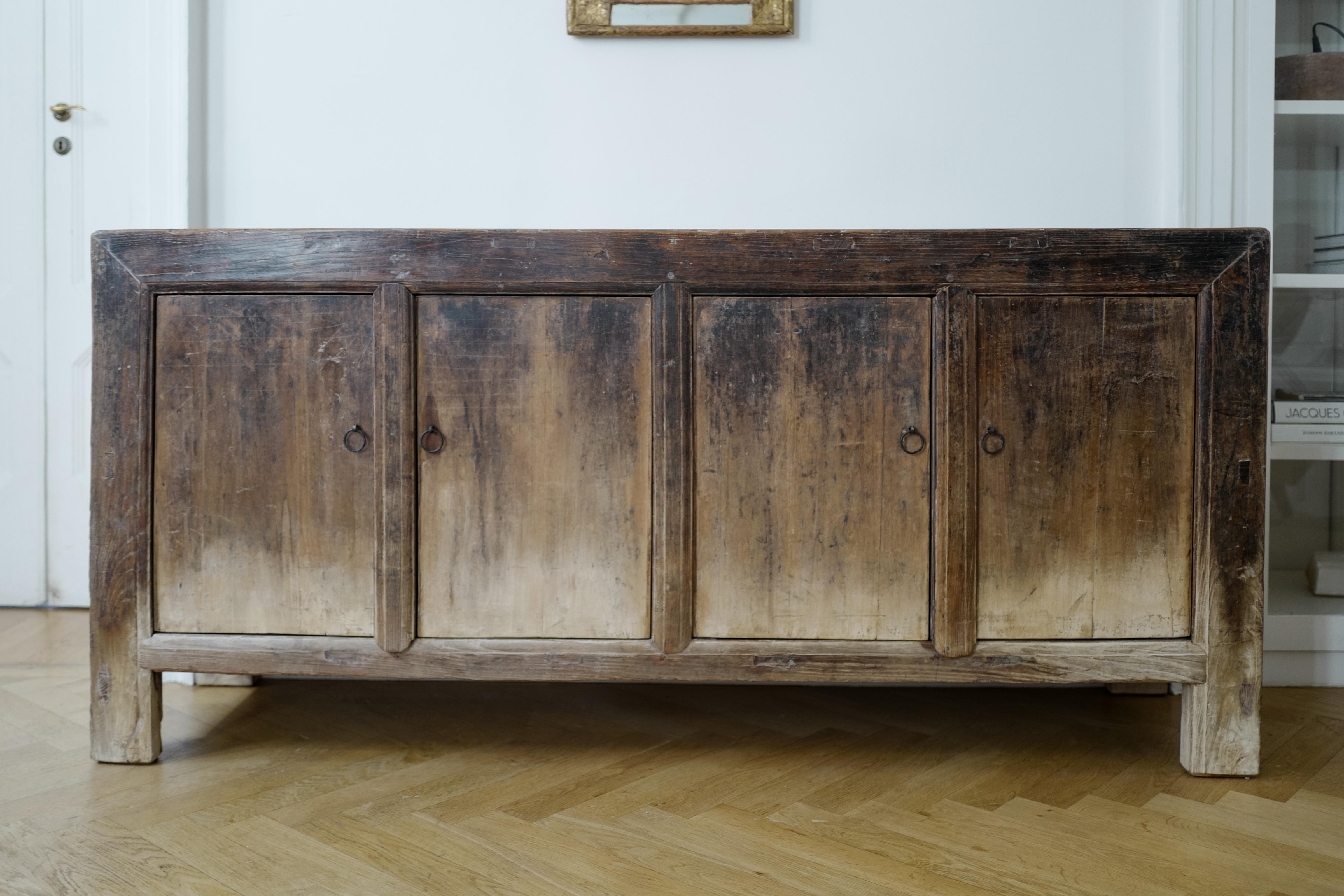 Questa credenza in legno di olmo cinese dell'inizio del XX secolo presenta una splendida patina naturale che ne evidenzia la ricca storia e l'eleganza senza tempo. Realizzata a mano in resistente legno di olmo, questa credenza antica esemplifica la