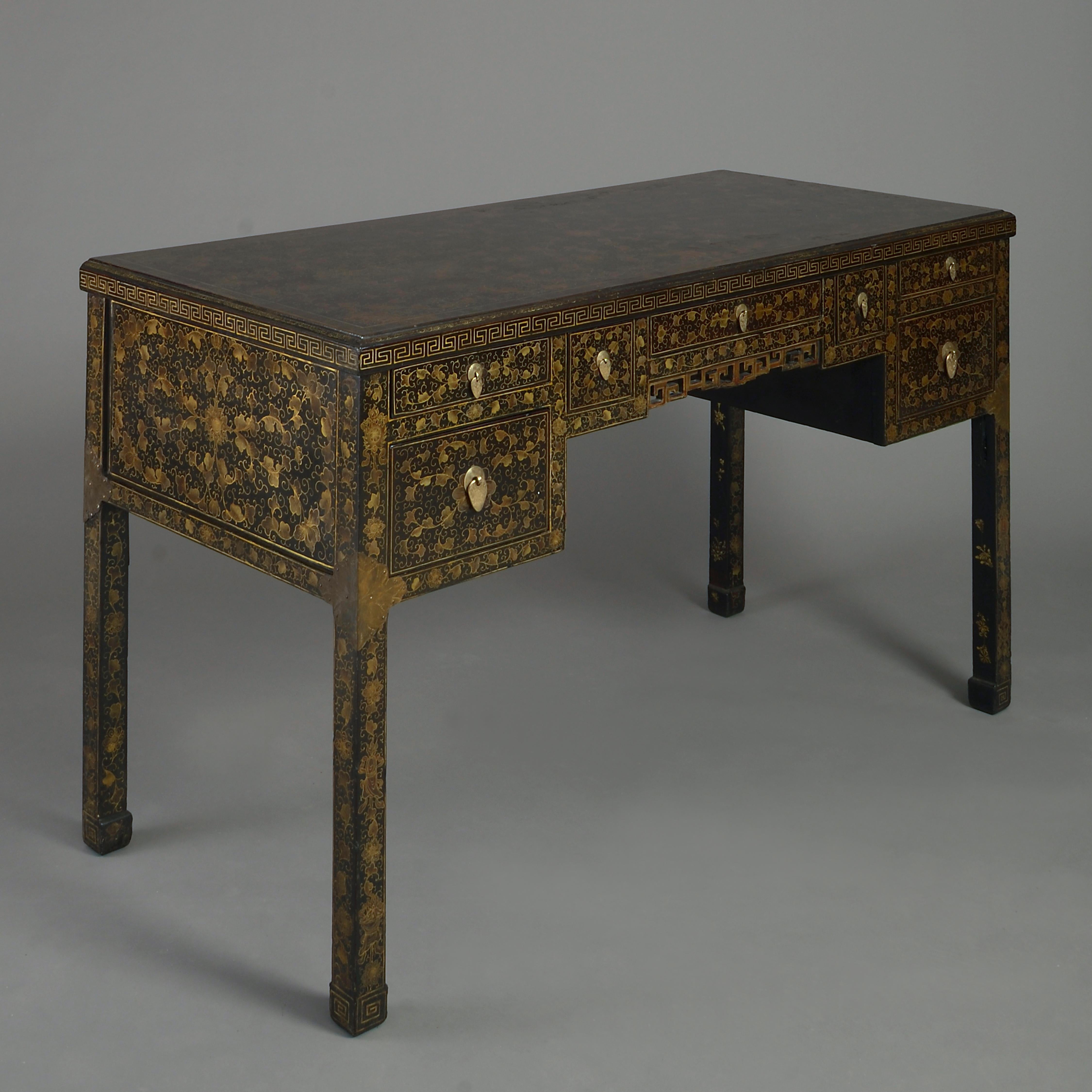 An early 20th century black lacquer bureau plat, the surfaces all with foliate gilt decoration upon a back ground, the front side with a configuration of seven drawers with brass drop handles, the sides and back all paneled, the whole raised upon